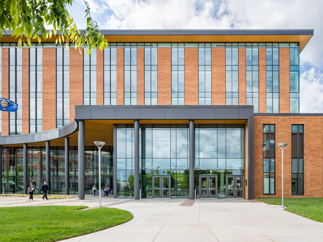 exterior photo of Clackamas County Courthouse; modern orange colored building with long and tall windows with an open glass entryway