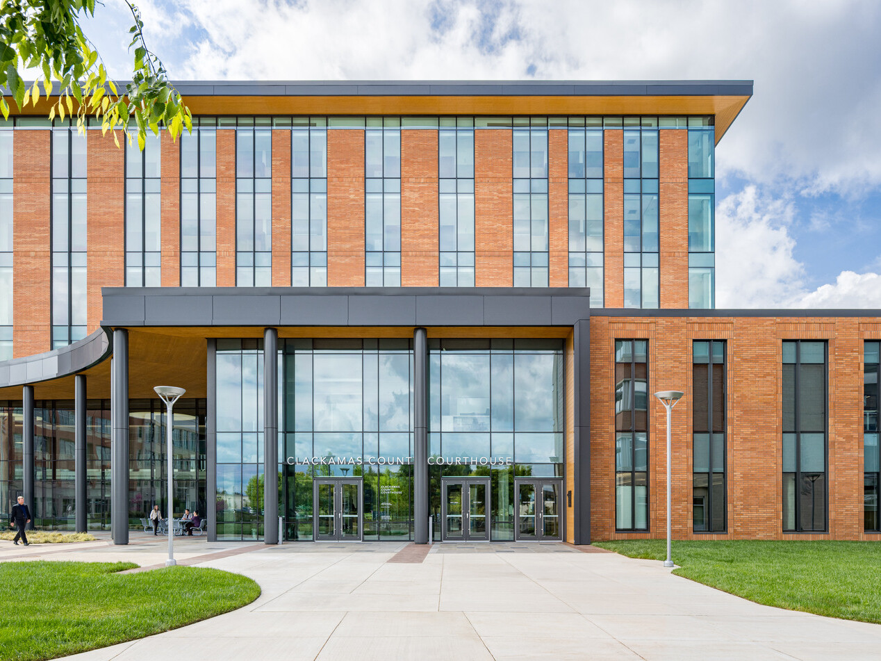 exterior photo of Clackamas County Courthouse; modern orange colored building with long and tall windows with an open glass entryway