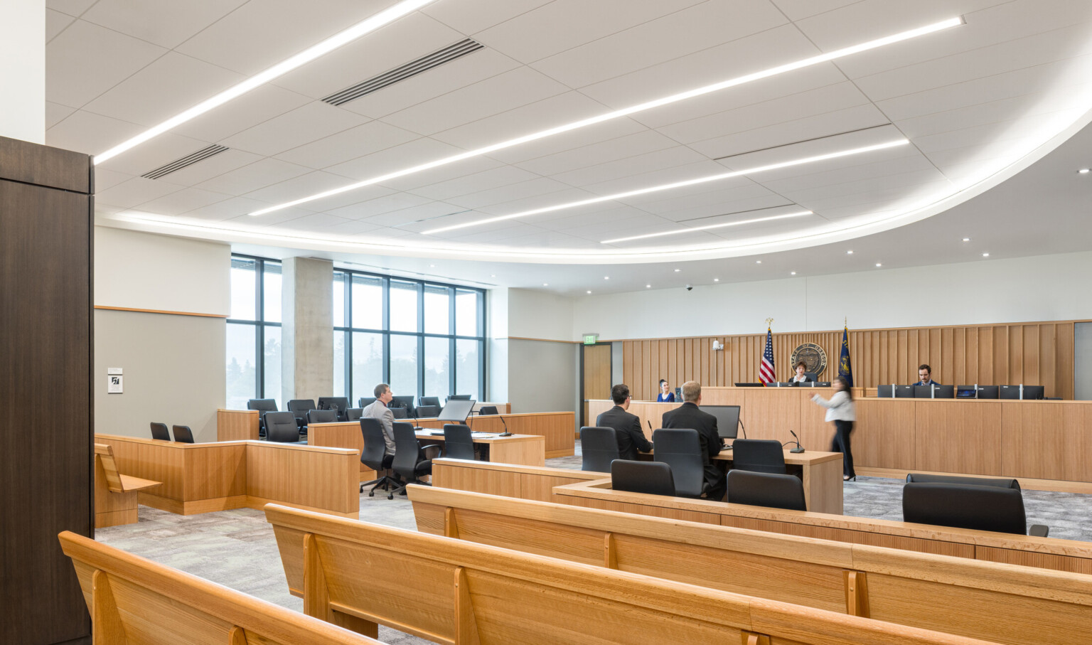 Clackamas County Courthouse modern court room; light timber bench seating facing the judge and witness stand; room side lit by large floor to ceiling windows