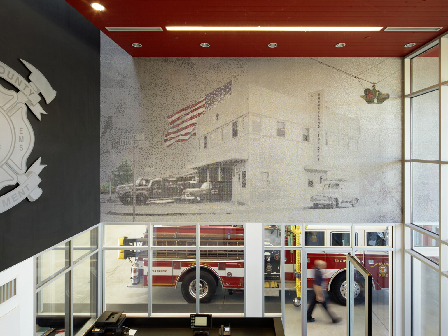 Interior of a fire station looking down onto a firetruck from a second story. Wall mural on a wall with red ceiling