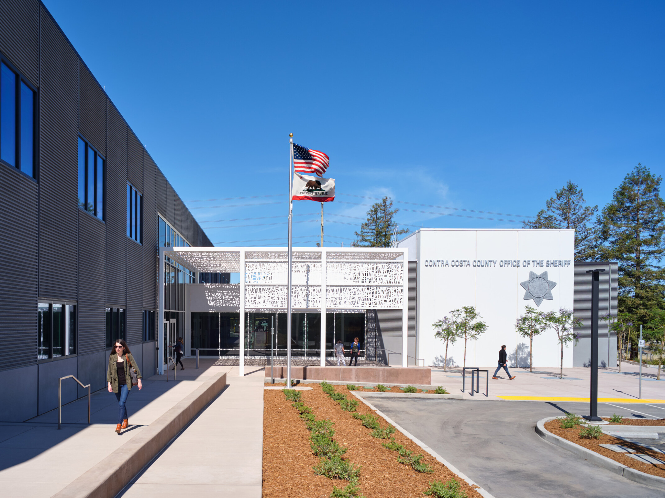 Multistory office building with a dark building to the left looking at a modern white building with words Contra Costa County Office of the Sheriff in sliver