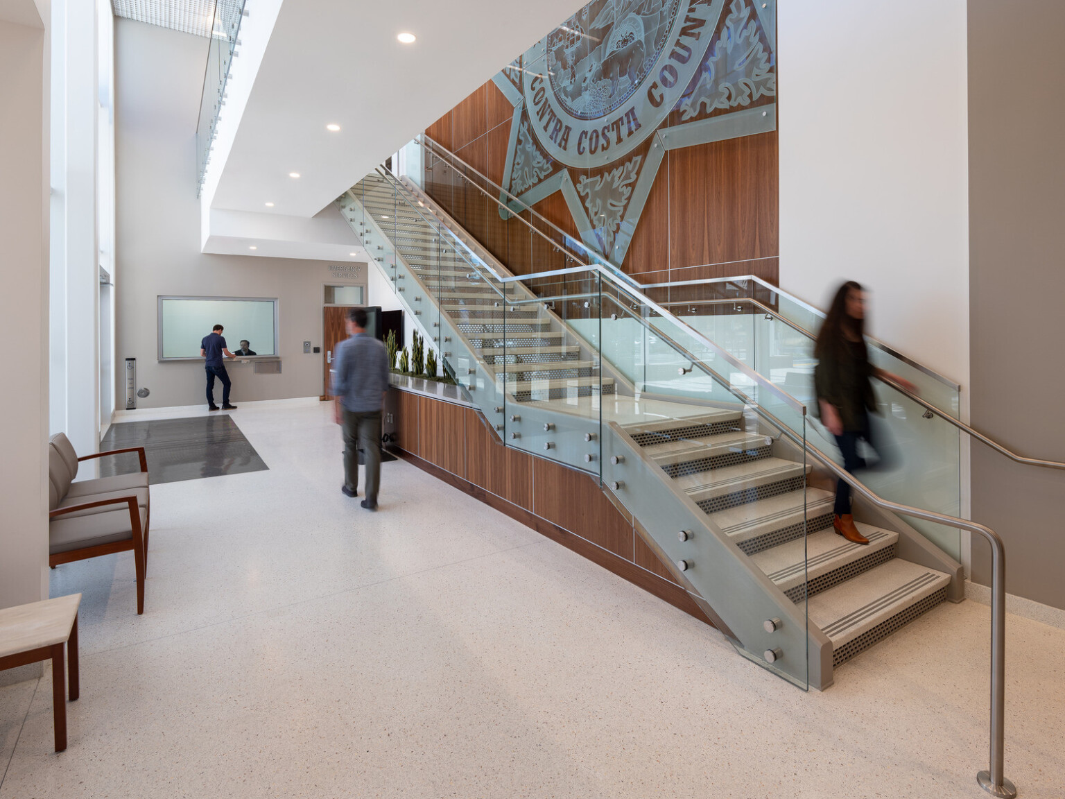 Interior of an office building with a staircase with glass railing with a wooden accent wall with sheriff seal