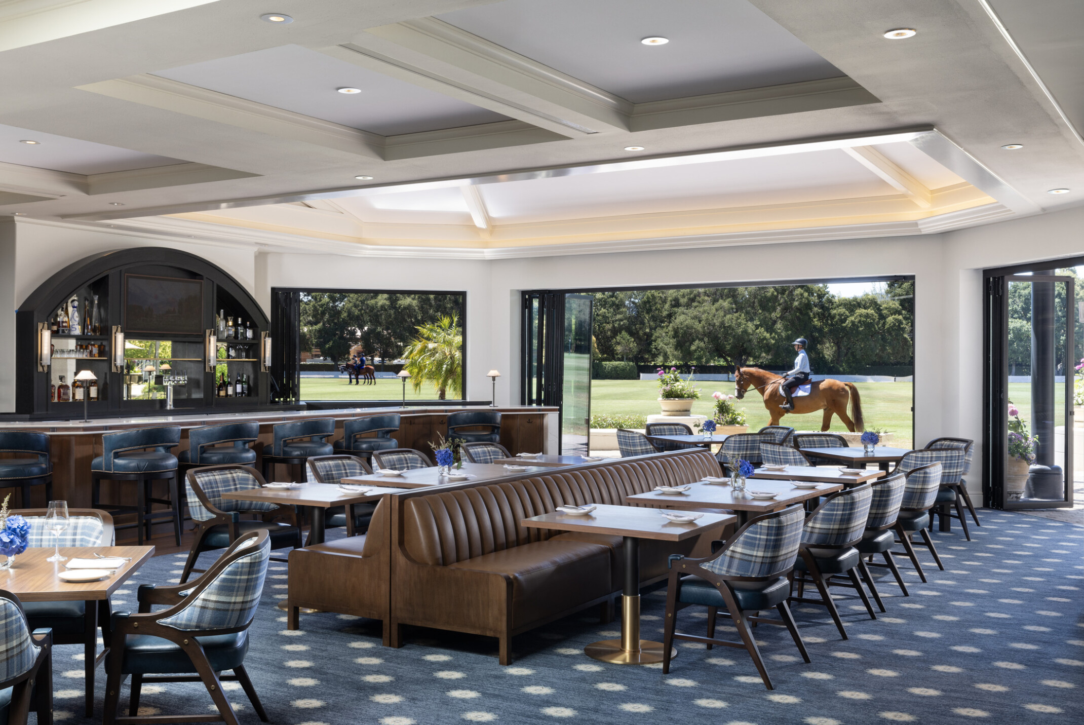 view from inside the dining room at a luxury country club, equestrian rider in background, blue carpet and wood details fill the space