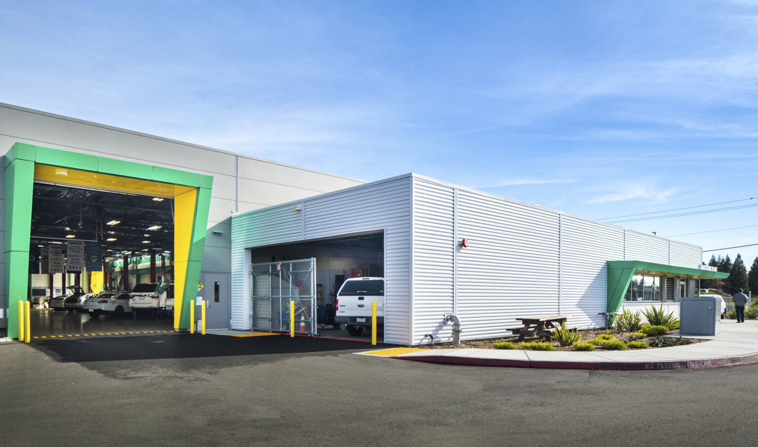 Exterior of garage door entrance to previous room with green and yellow awning, left. Main building entrance to right