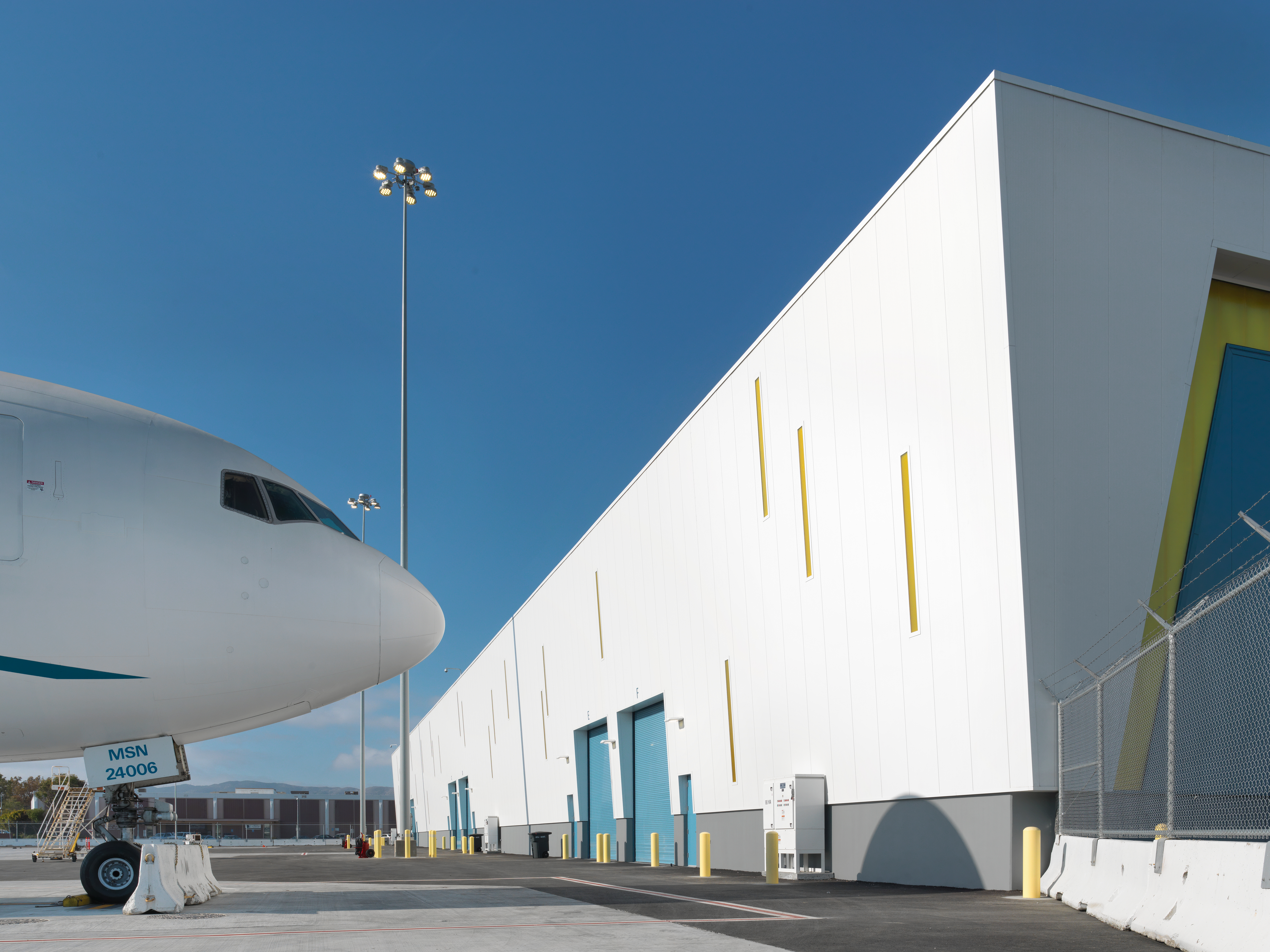 nose of an airplane against a blue sky; next to a white building