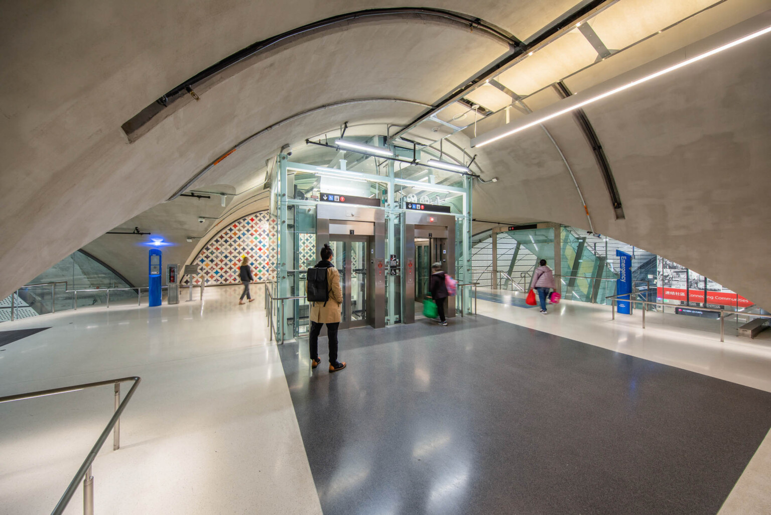 Domed upper level tunnel with stairs, back right, behind elevator shaft under construction. Raw concrete ceiling and floor