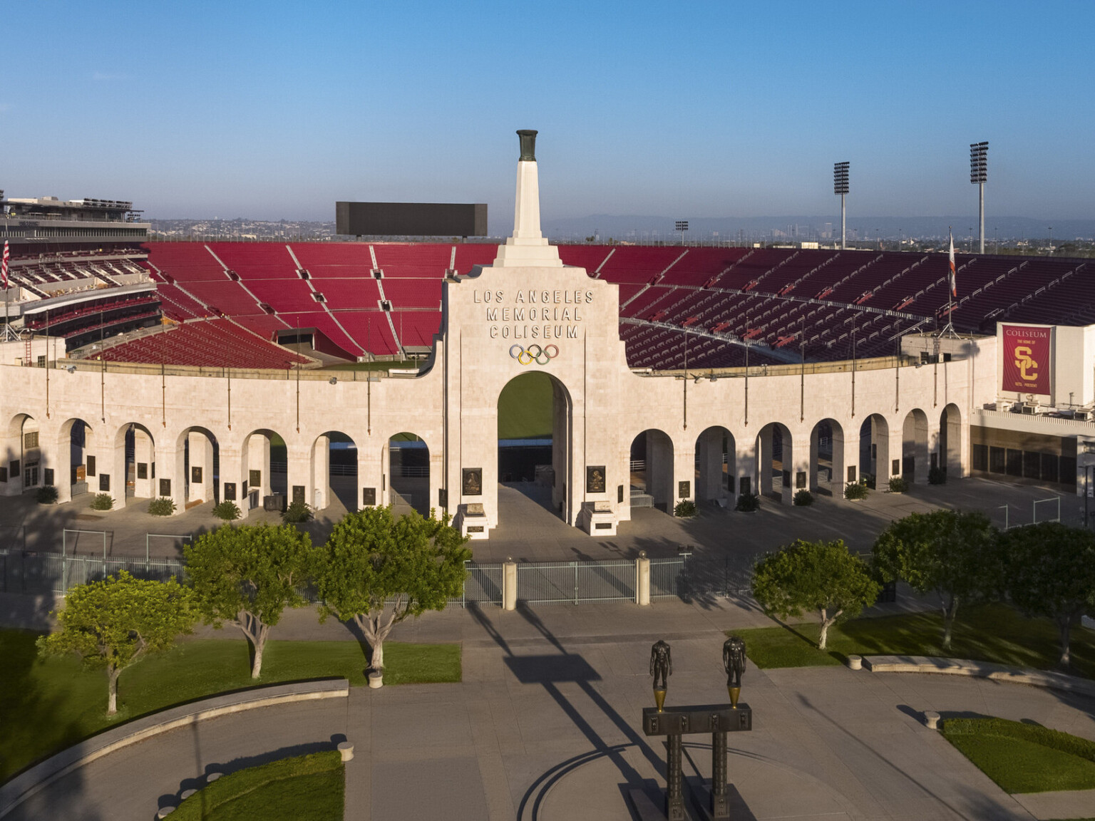 Front of stadium with Robert Graham sculpture Olympic Gateway at center of round plaza with greenery and arched entryway