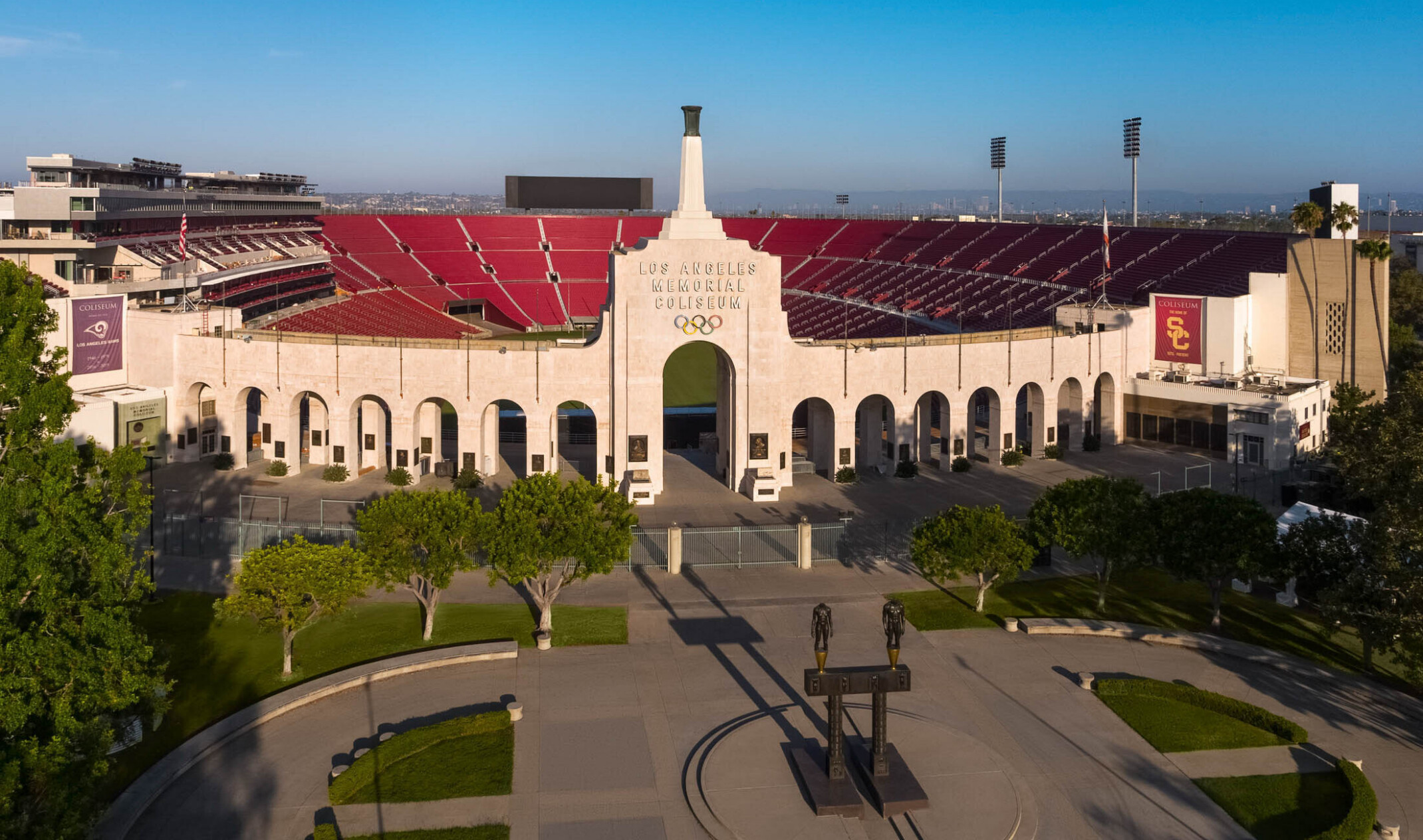 Front of stadium with Robert Graham sculpture Olympic Gateway at center of round plaza with greenery and arched entryway