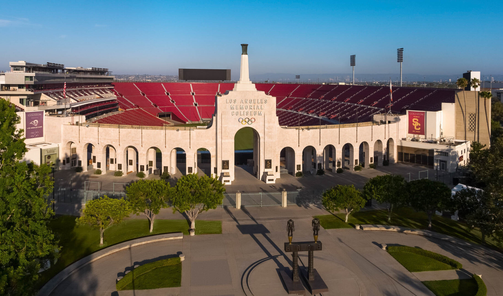 Front of stadium with Robert Graham sculpture Olympic Gateway at center of round plaza with greenery and arched entryway