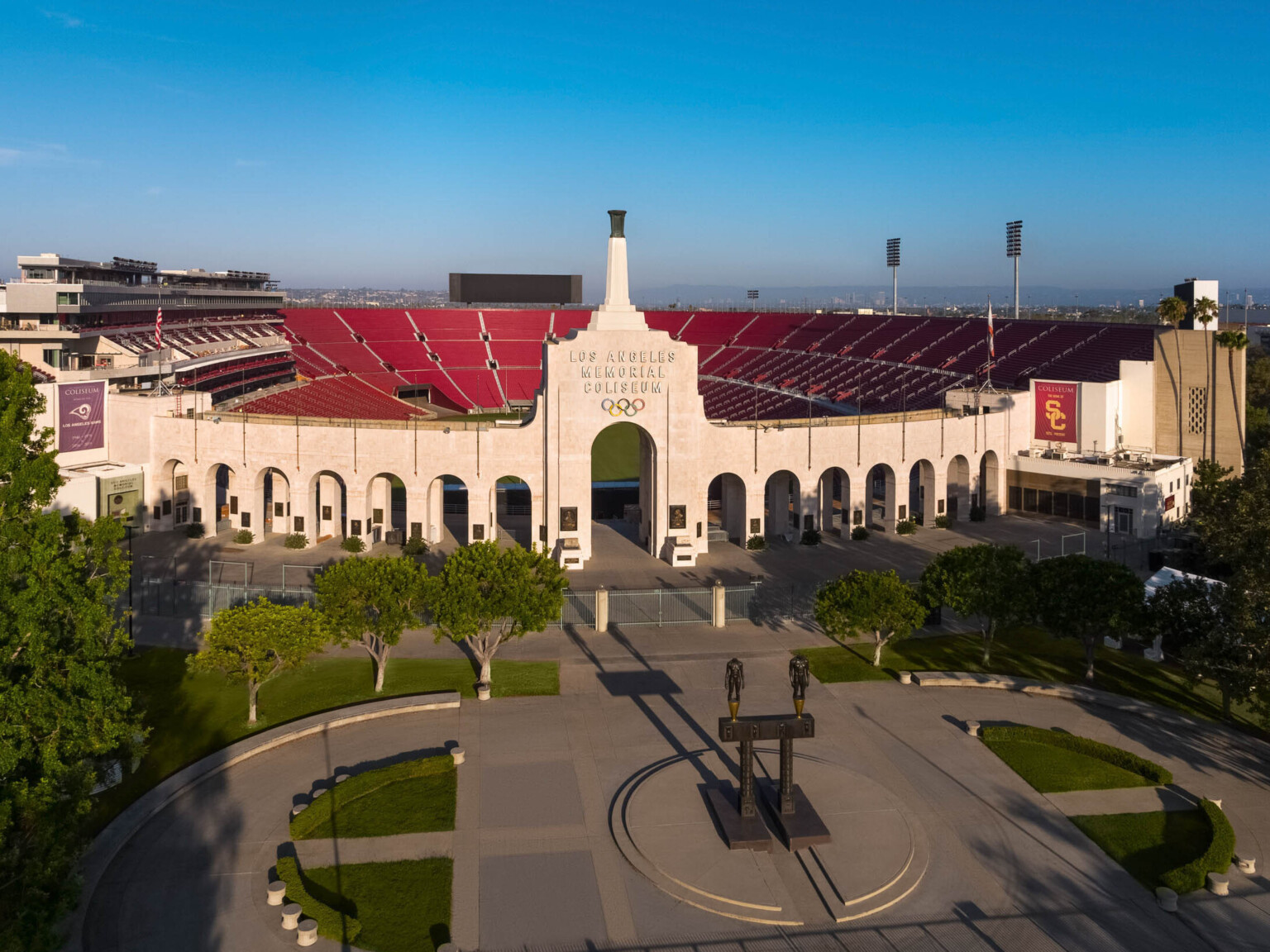 Front of stadium with Robert Graham sculpture Olympic Gateway at center of round plaza with greenery and arched entryway