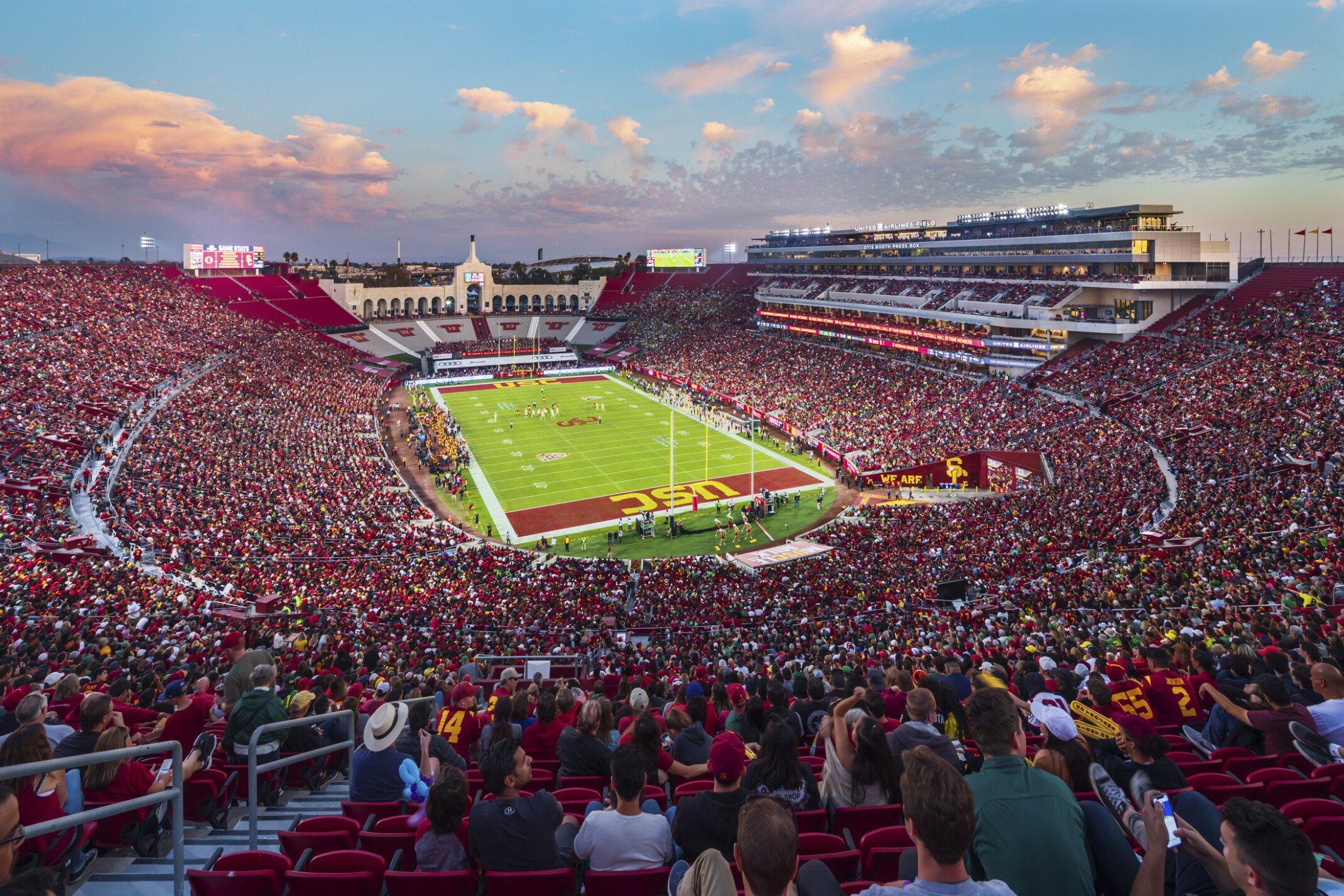 Full stadium of fans in red during dusk football game at the LA Memorial Coliseum