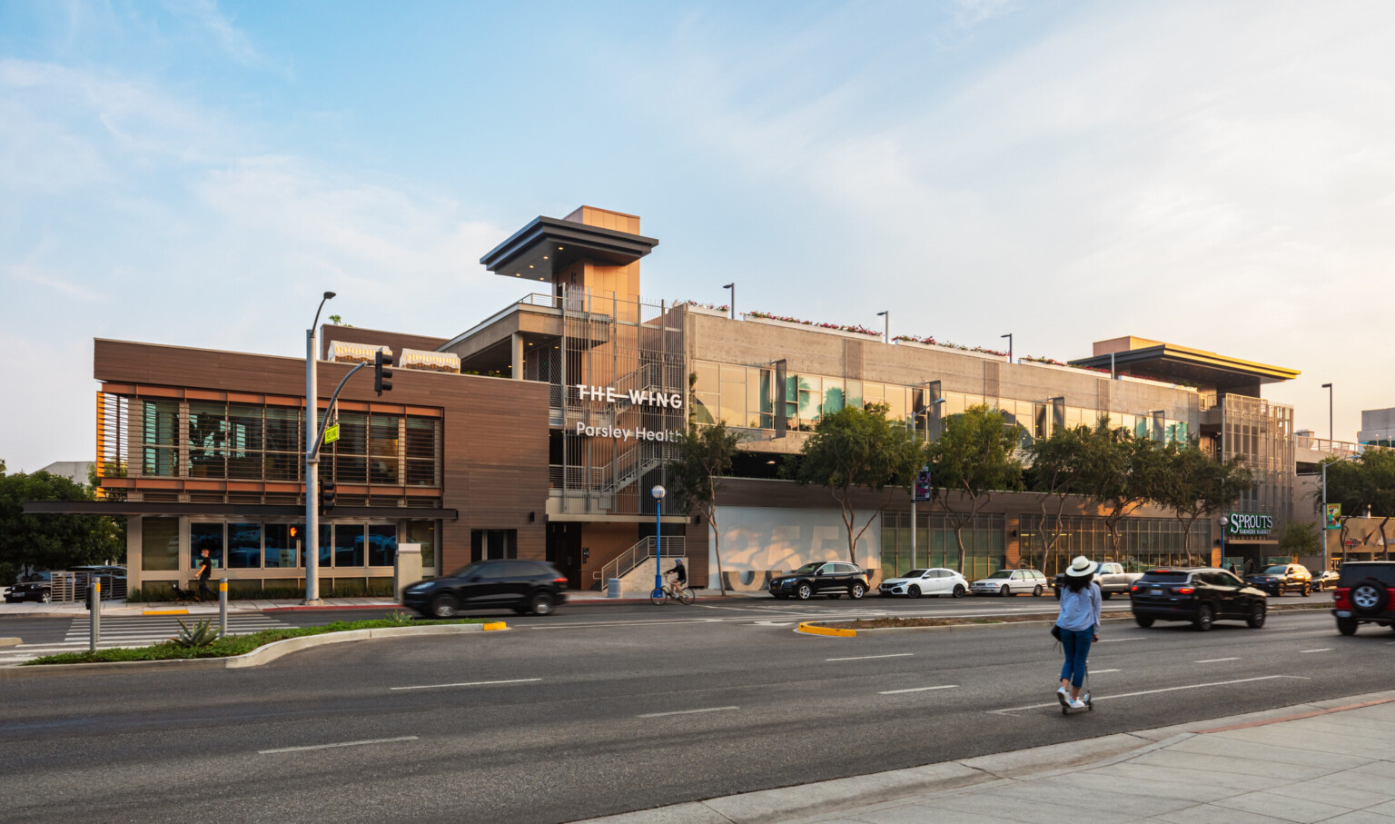 Front facade of a multi-story building; A white sign with "The Wing" against the neutral wood and stone materials of the building