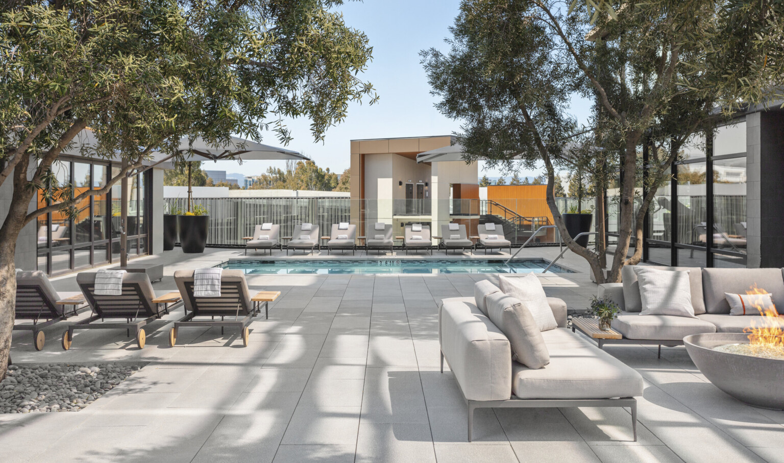 Lush landscaping, lounge seating, and firepit surround heated outdoor pool.