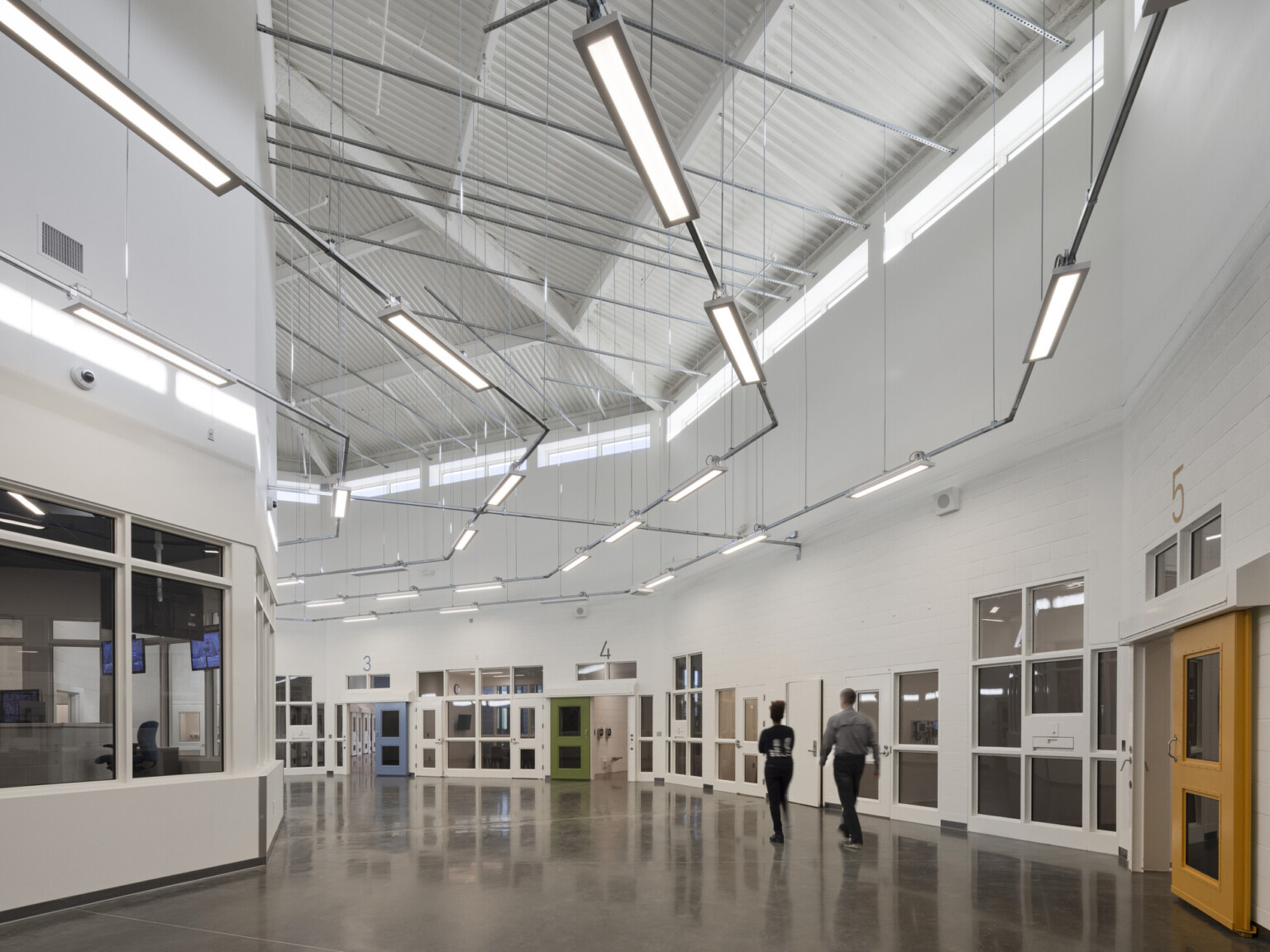 interior of Health & Programming Unit hallway with high-ceilings, polished concrete flooring, custom curved overhead lighting