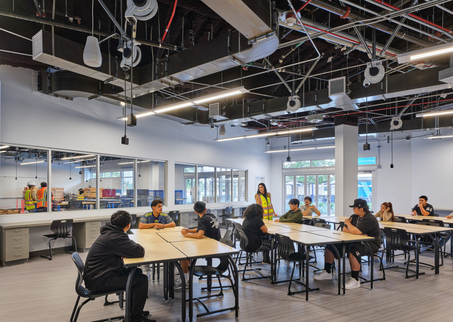 Classroom filled with students at tables collaborating and working; blue and white accents on the floor and walls; Compton High School