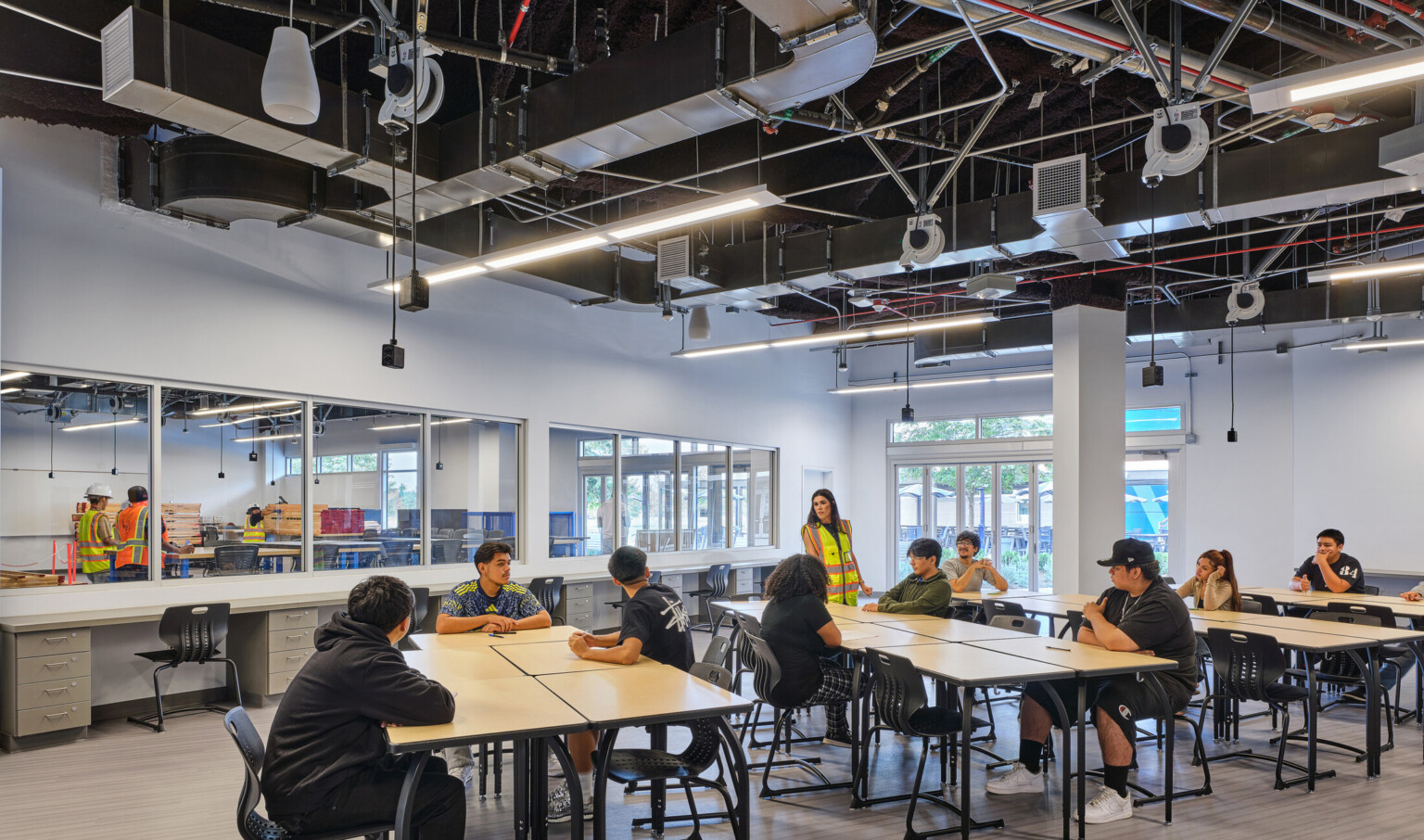 Classroom filled with students at tables collaborating and working; blue and white accents on the floor and walls; Compton High School