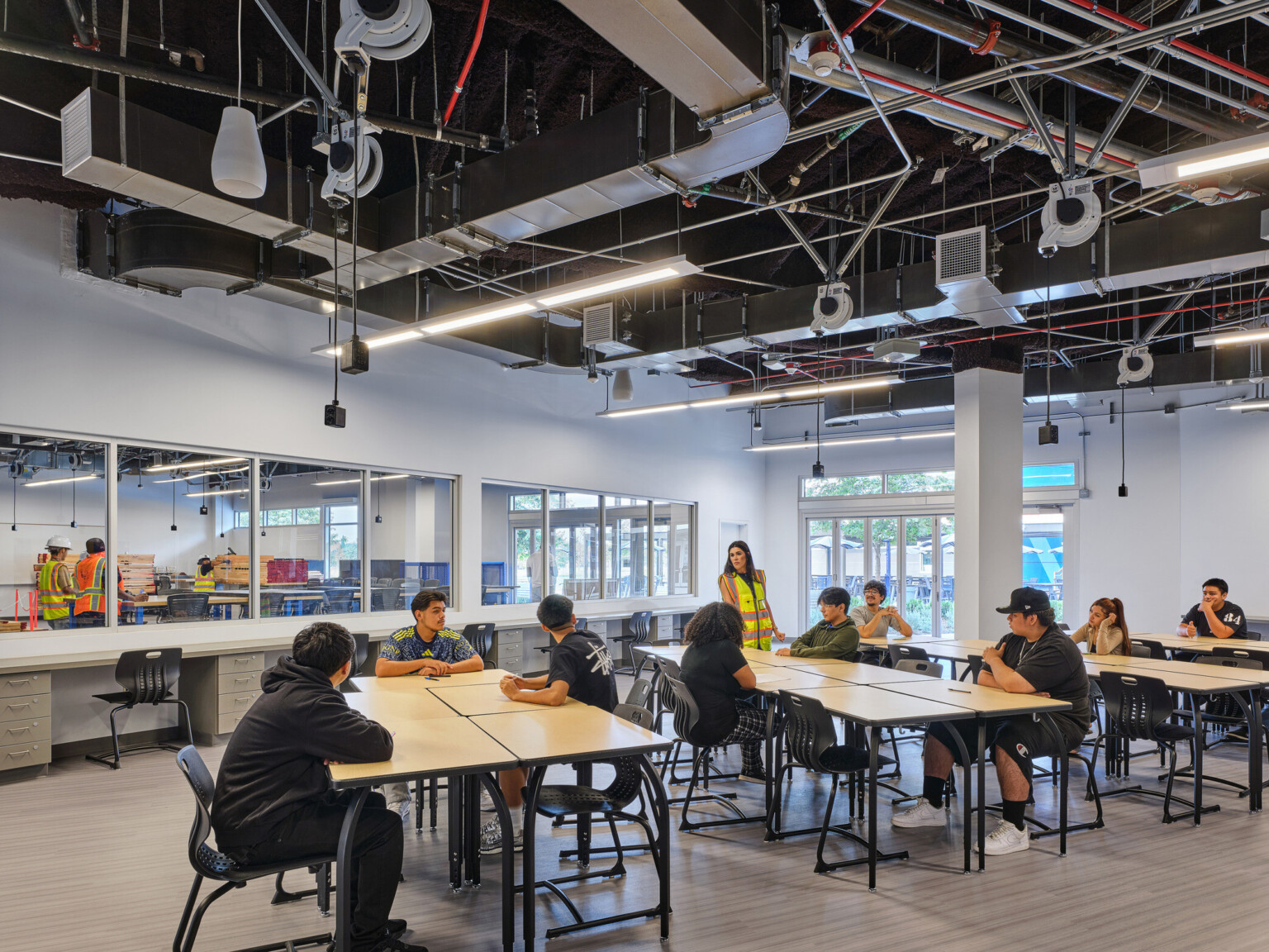 Classroom filled with students at tables collaborating and working; blue and white accents on the floor and walls; Compton High School