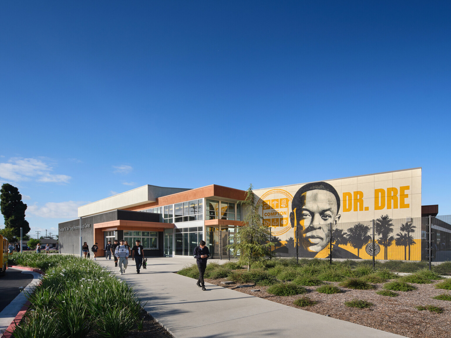 Compton High School Andrew "Dr. Dre" Young Performing Arts Center entrance; modern building with a Dr. Dre mural on the front facing exterior wall; performing arts community center