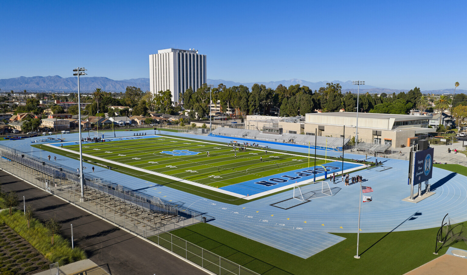 Football field of Compton High School; blue track surrounds the green field with blue "COMPTON" end zones