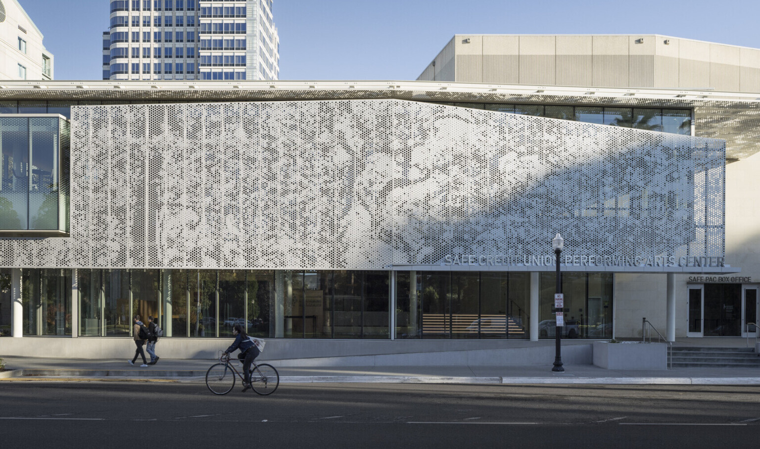 Perforated façade on a large two-story building in Sacramento. Perforated white metal scrim on the exterior shades from the sun. First floor open to the street with full glass windows.