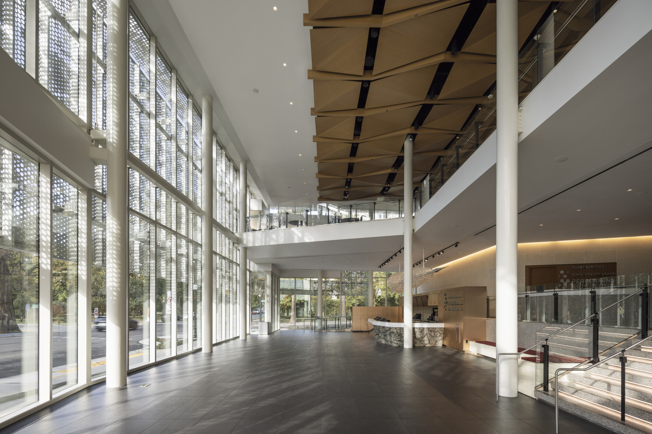 interior lobby with double height floor to ceiling glass store fronts and custom wood ceiling over a mezzanine