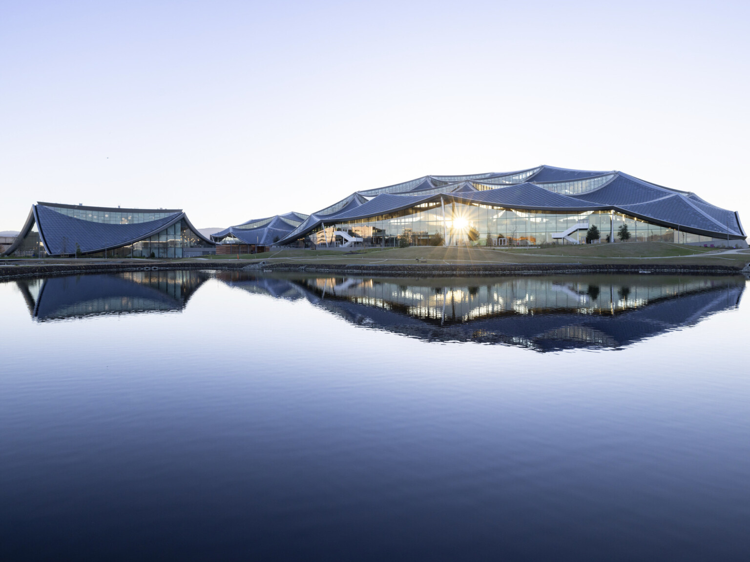 Three round buildings with rounded angular sloping roofs in a flat valley buildings reflected in a small body of water