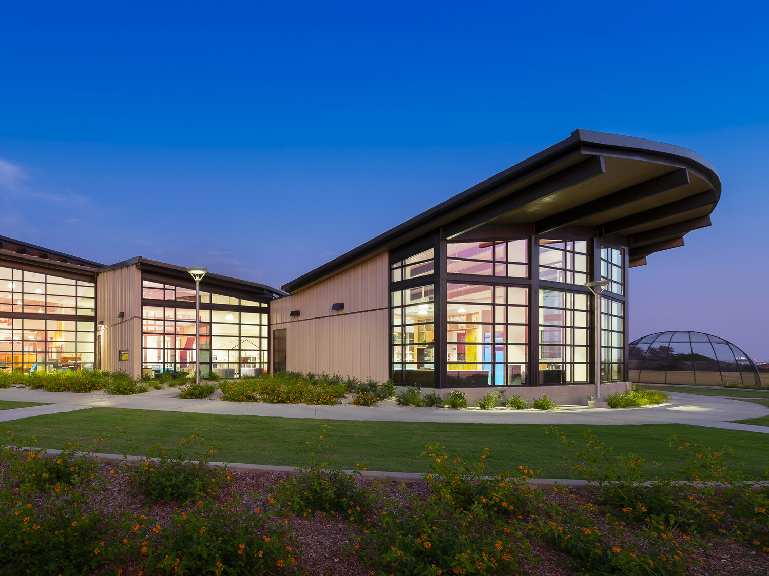 exterior of Del Mar Heights School at night, architecture inspired by California Coastal Architecture; indoor outdoor learning space with large openable windows