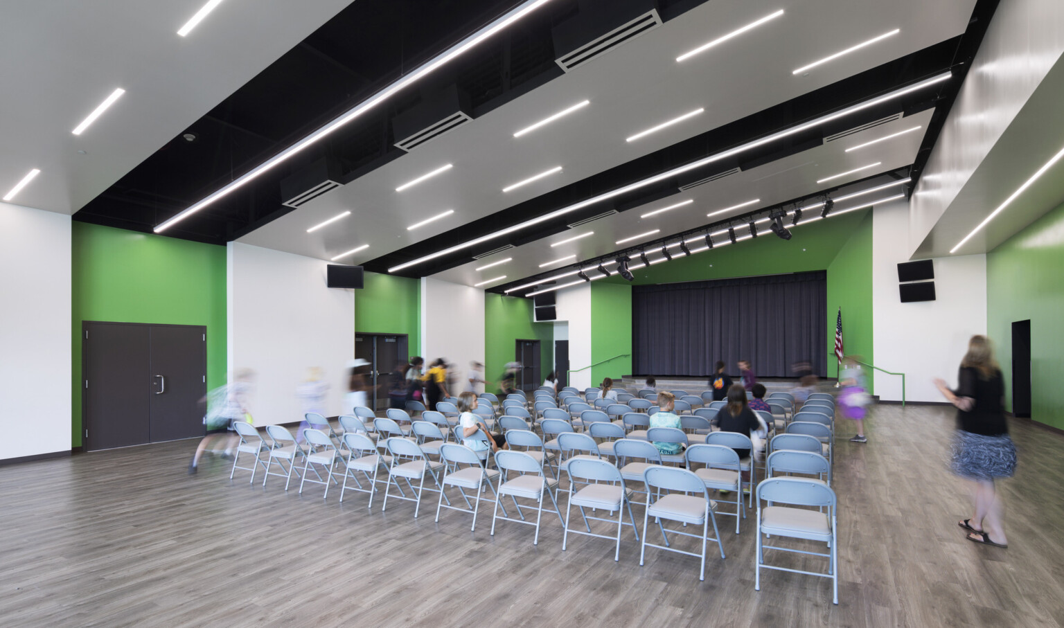 Richland Elementary School Auditorium; folding chairs facing small black stage bright green wall accents Richland Elementary School Auditorium; folding chairs facing small black stage bright green wall accents