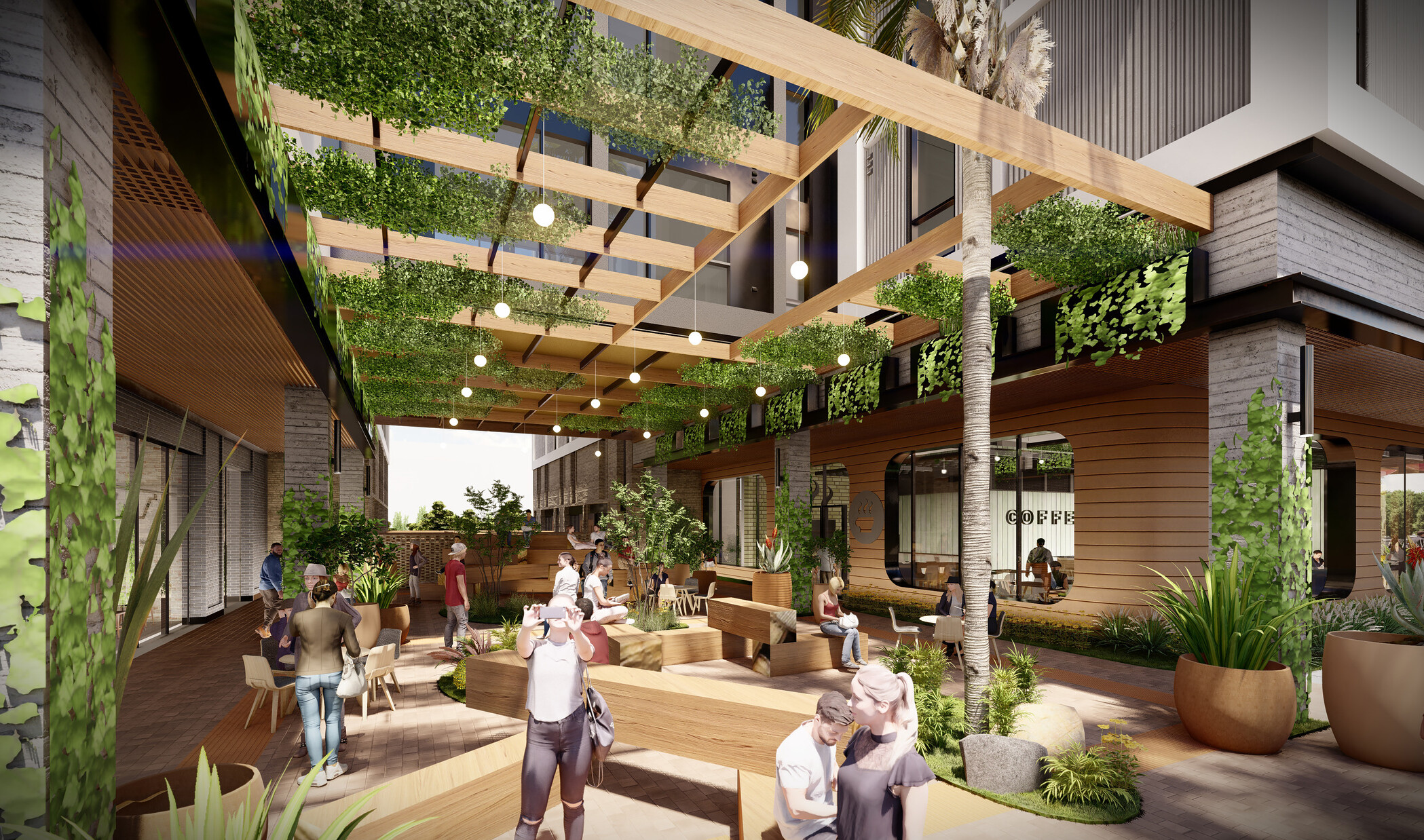 View from under canopy frame with hanging greenery and landscaped plants. Wood benches, chairs, tables, in common space