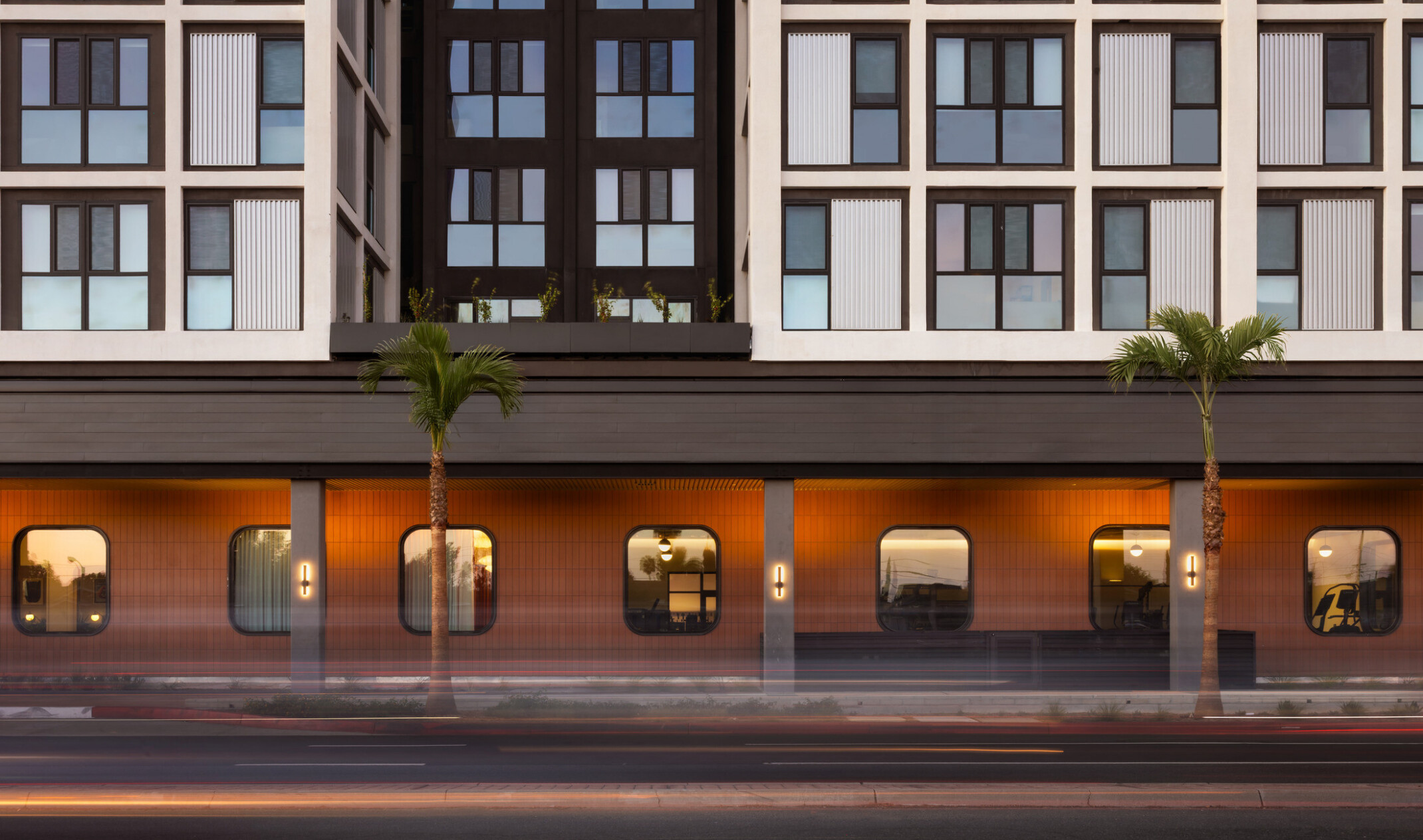 Straight-on view of Hub Fullerton's lower façade, featuring rounded corner windows and a light well recessed into the building to bring daylight into interior spaces.