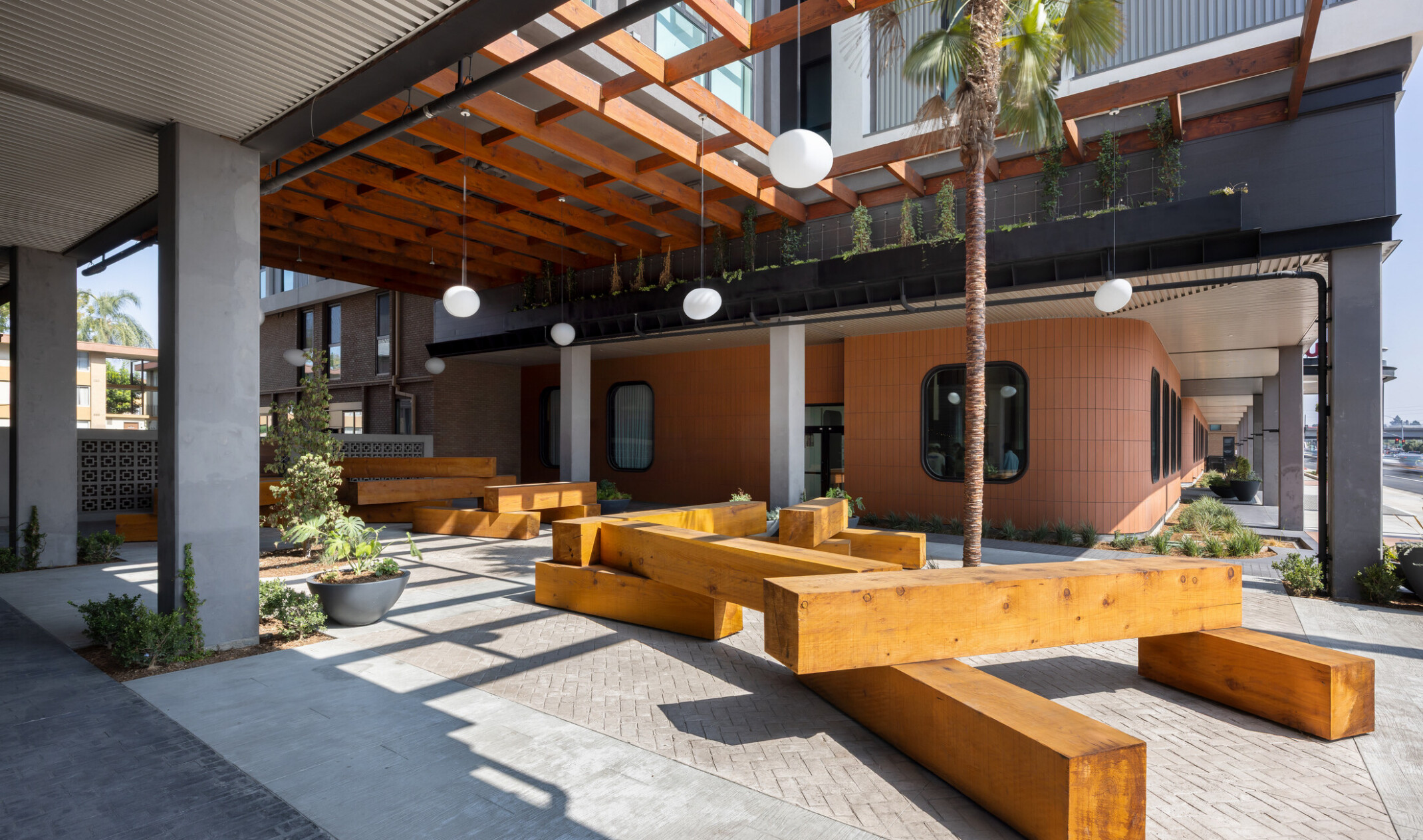 Unoccupied view of Hub Fullerton's paseo, with landscaping beginning to climb toward a slatted ceiling overhead.