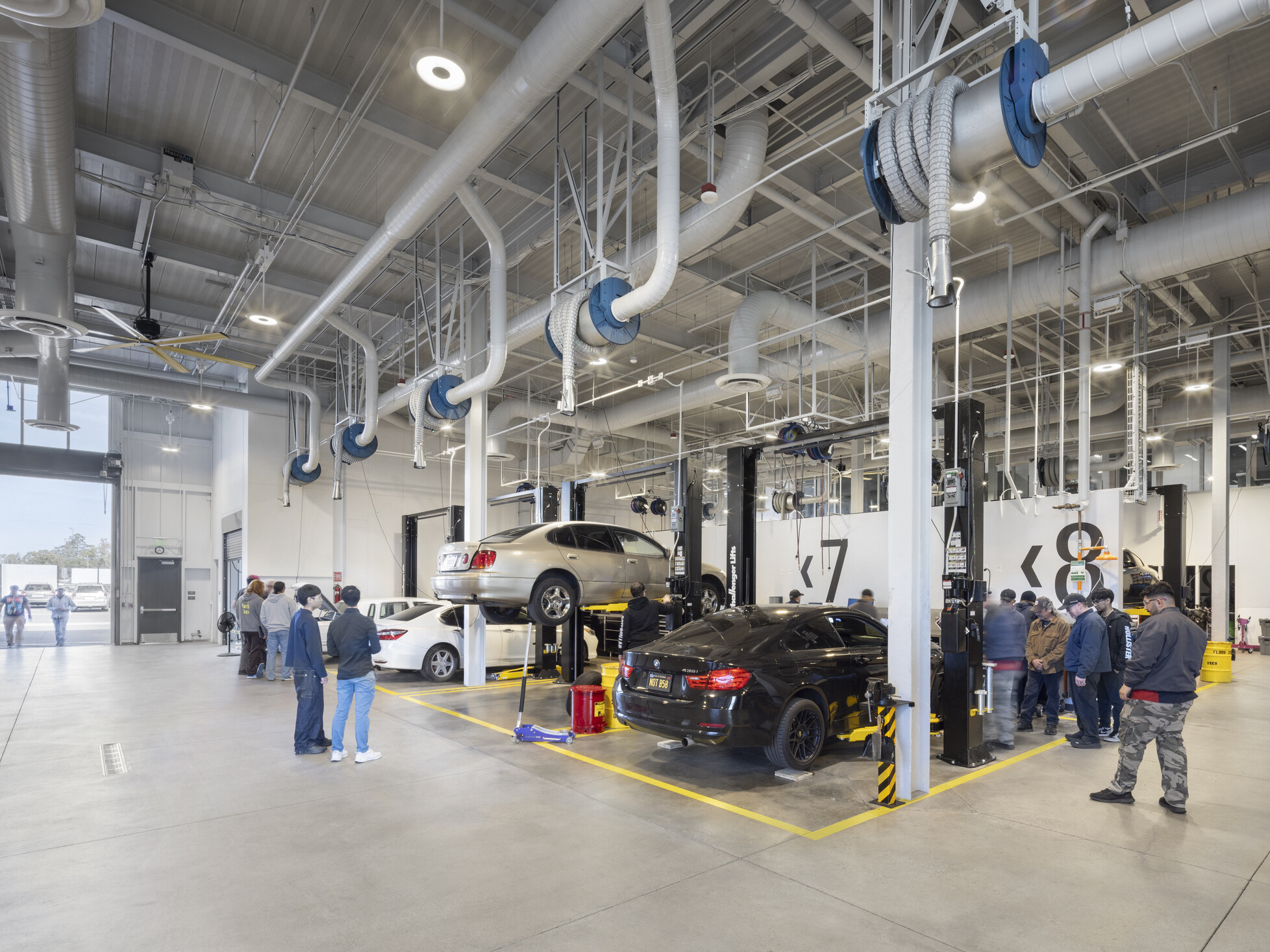indoor/outdoor classroom of a technical career education space; motor vehicle work space; industrial feel with specialized tools and stations