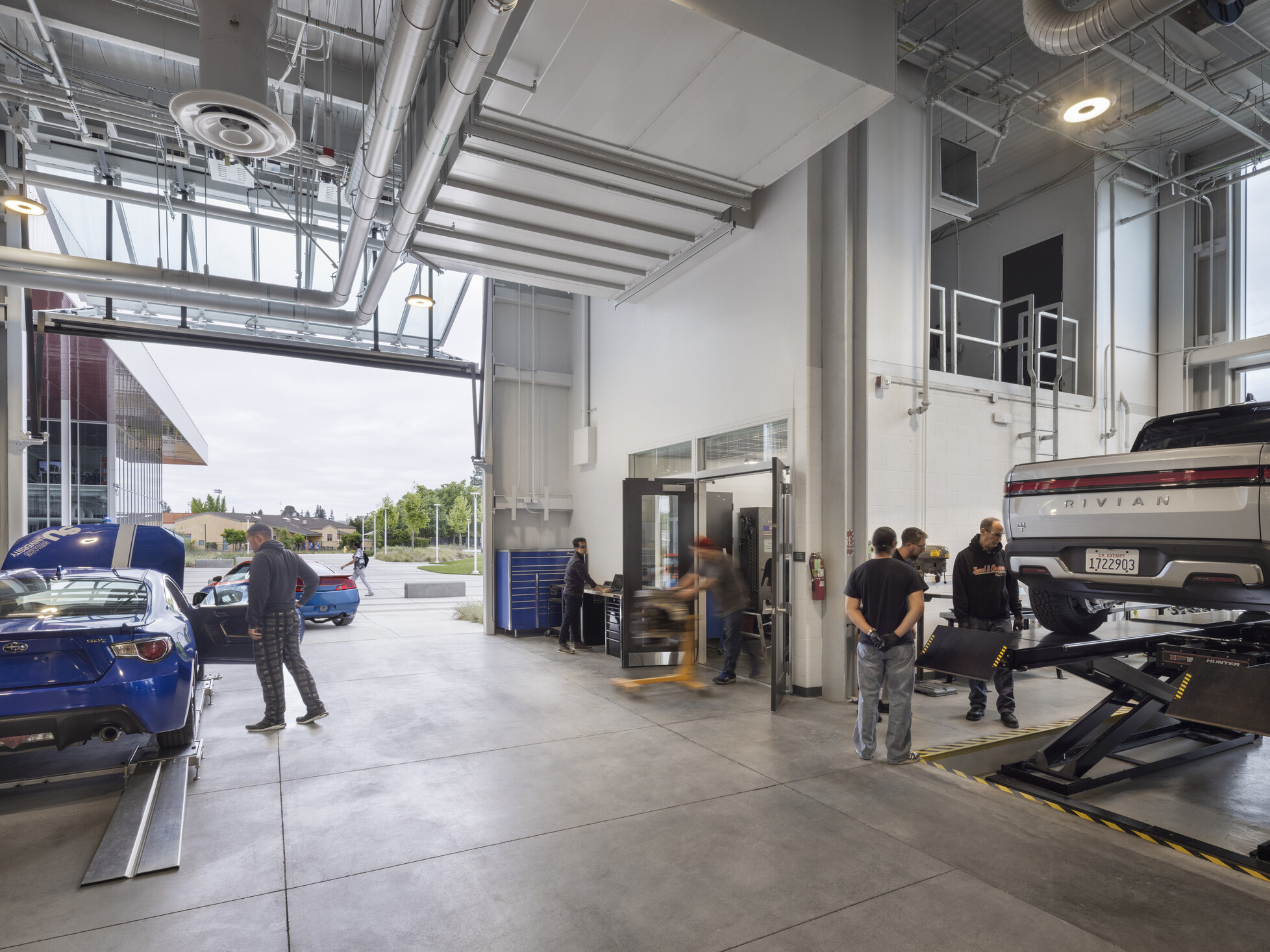 indoor/outdoor classroom of a technical career education space; motor vehicle work space; industrial feel with specialized tools and stations