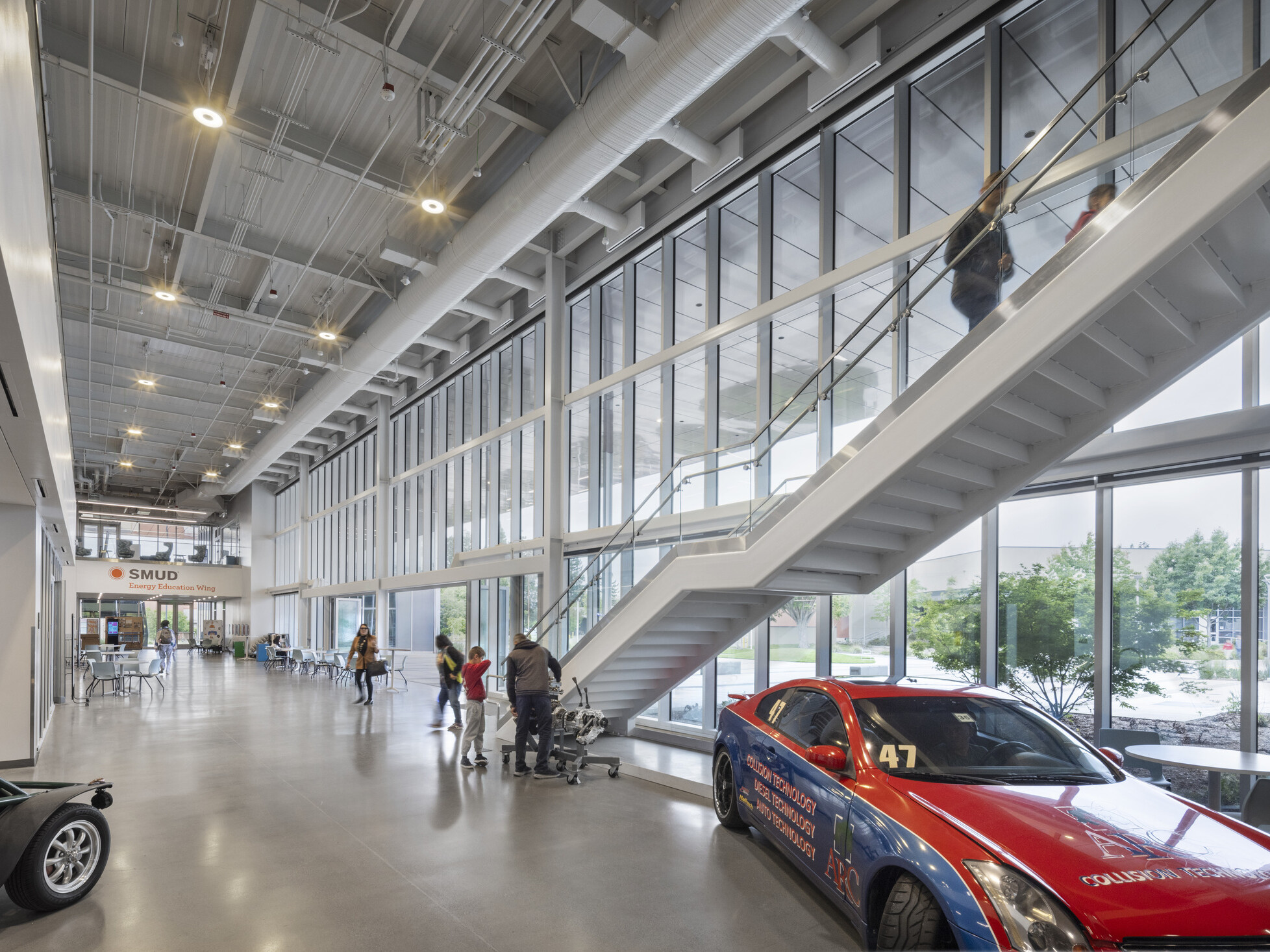 large open technical education hallway with exposed architectural elements and display cars