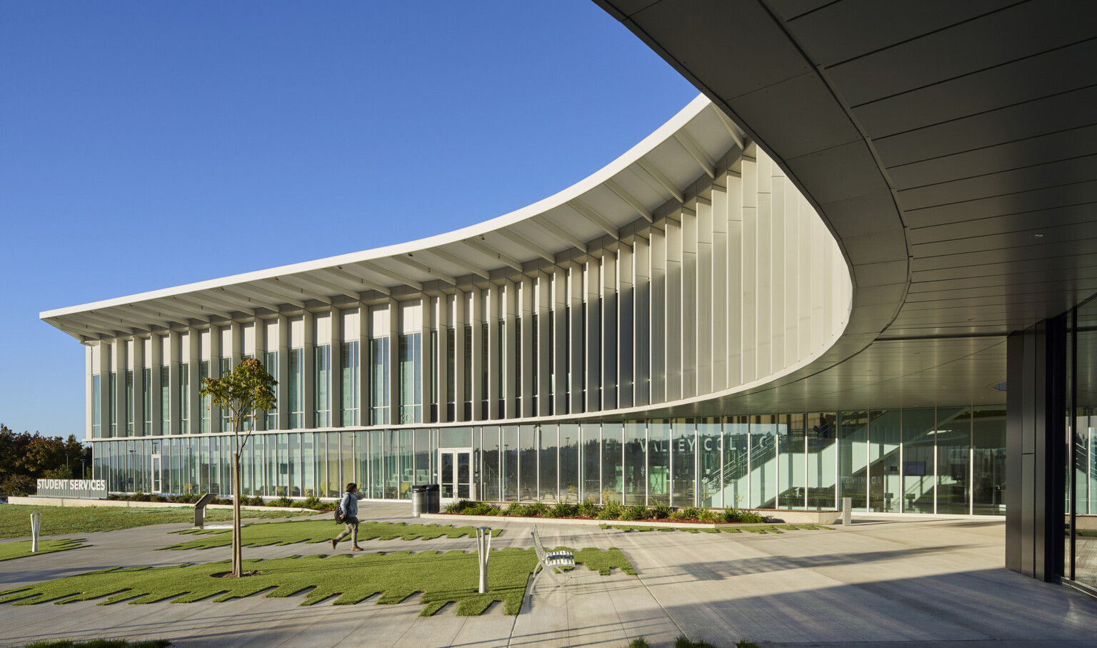Multistory modern building with large glass panels and a curved roof Multistory modern building with large glass panels and a curved roof