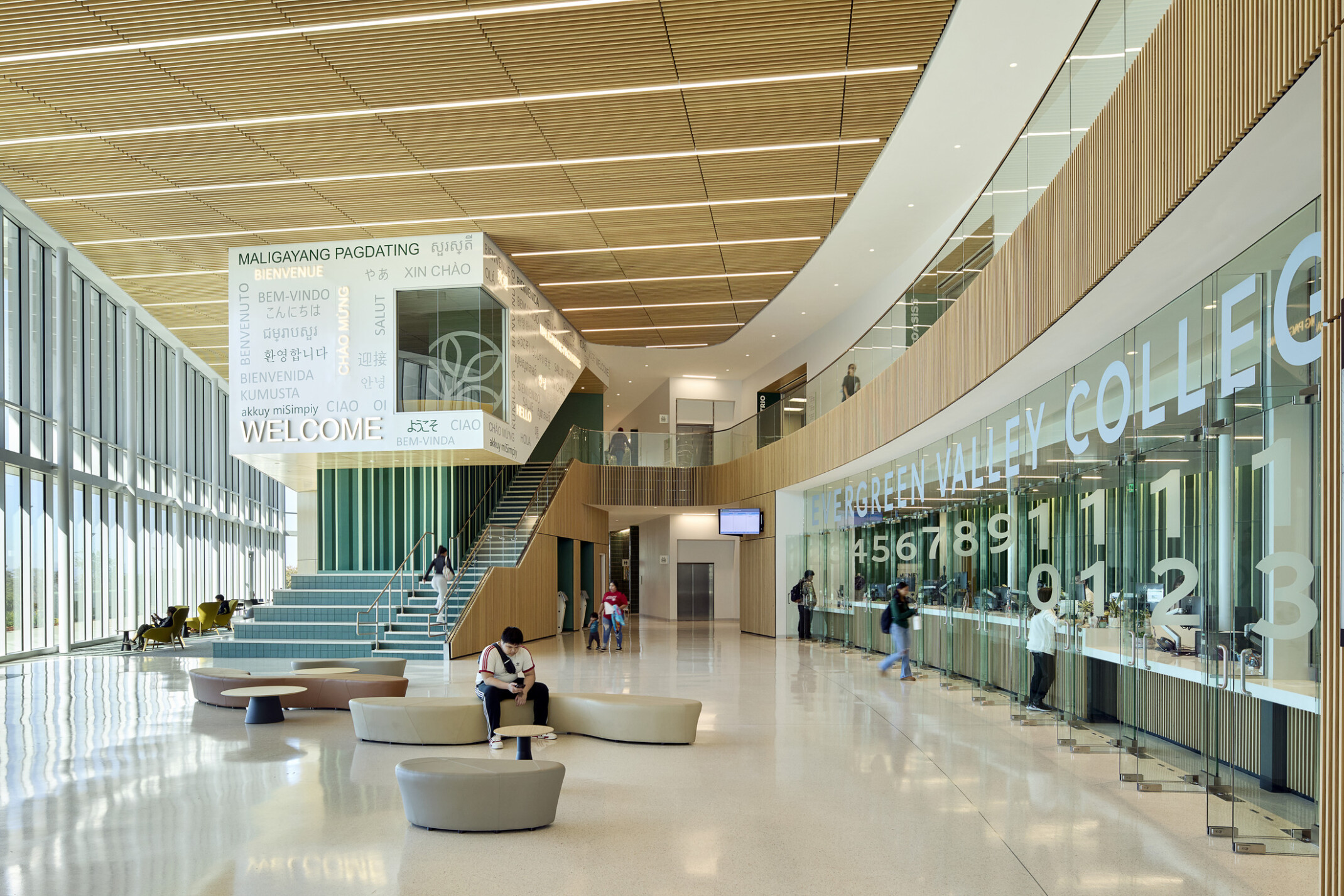 large double height atrium lobby area; floor to ceiling windows; natural palette of materials decorate space