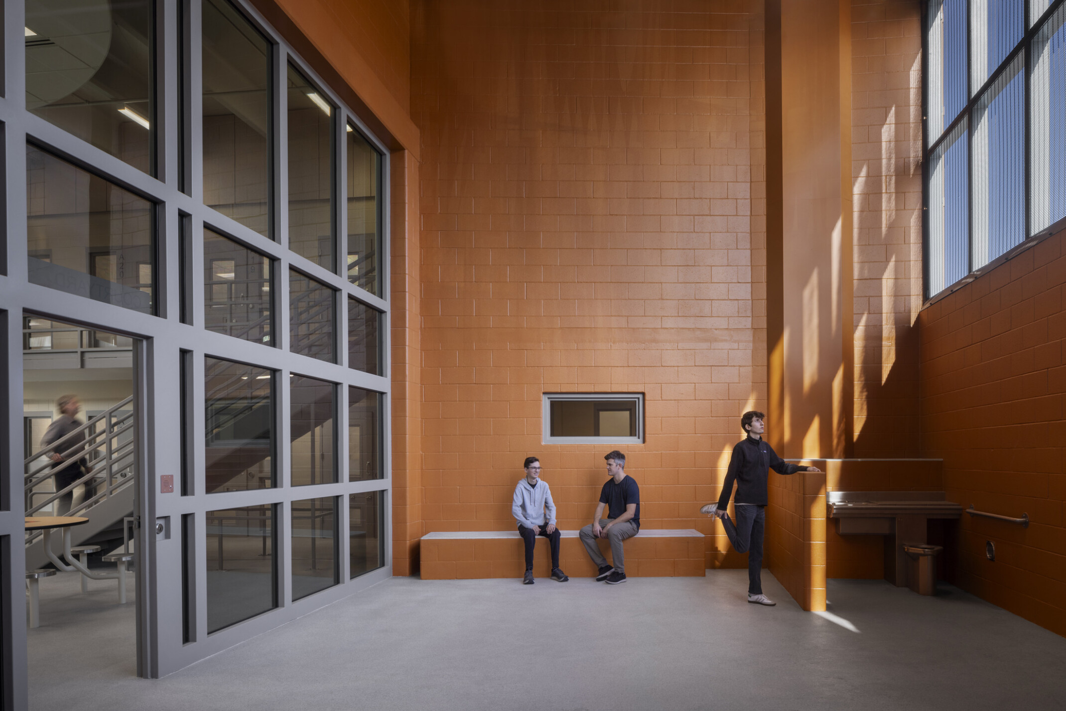 Outdoor recreation space adjacent to the housing dayroom; burnt orange brick walls and large windows surround the space.