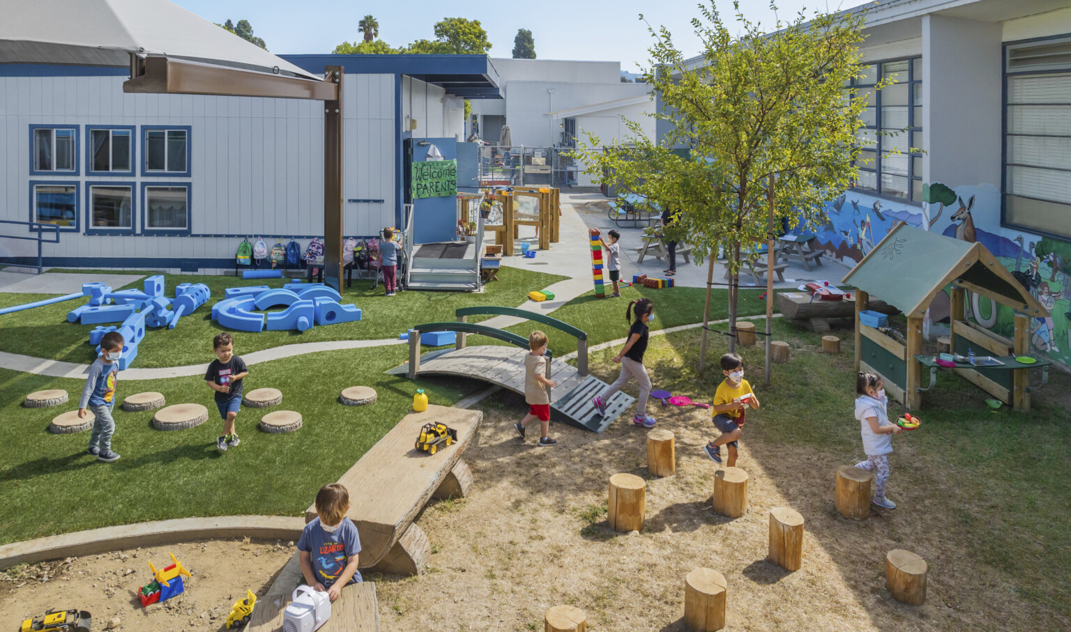 Children enjoying outdoor learning at Culver City Amazon Playground with custom sandbox, a bridge and surrounded by sunny skies Children enjoying outdoor learning at Culver City Amazon Playground with custom sandbox, a bridge and surrounded by sunny skies