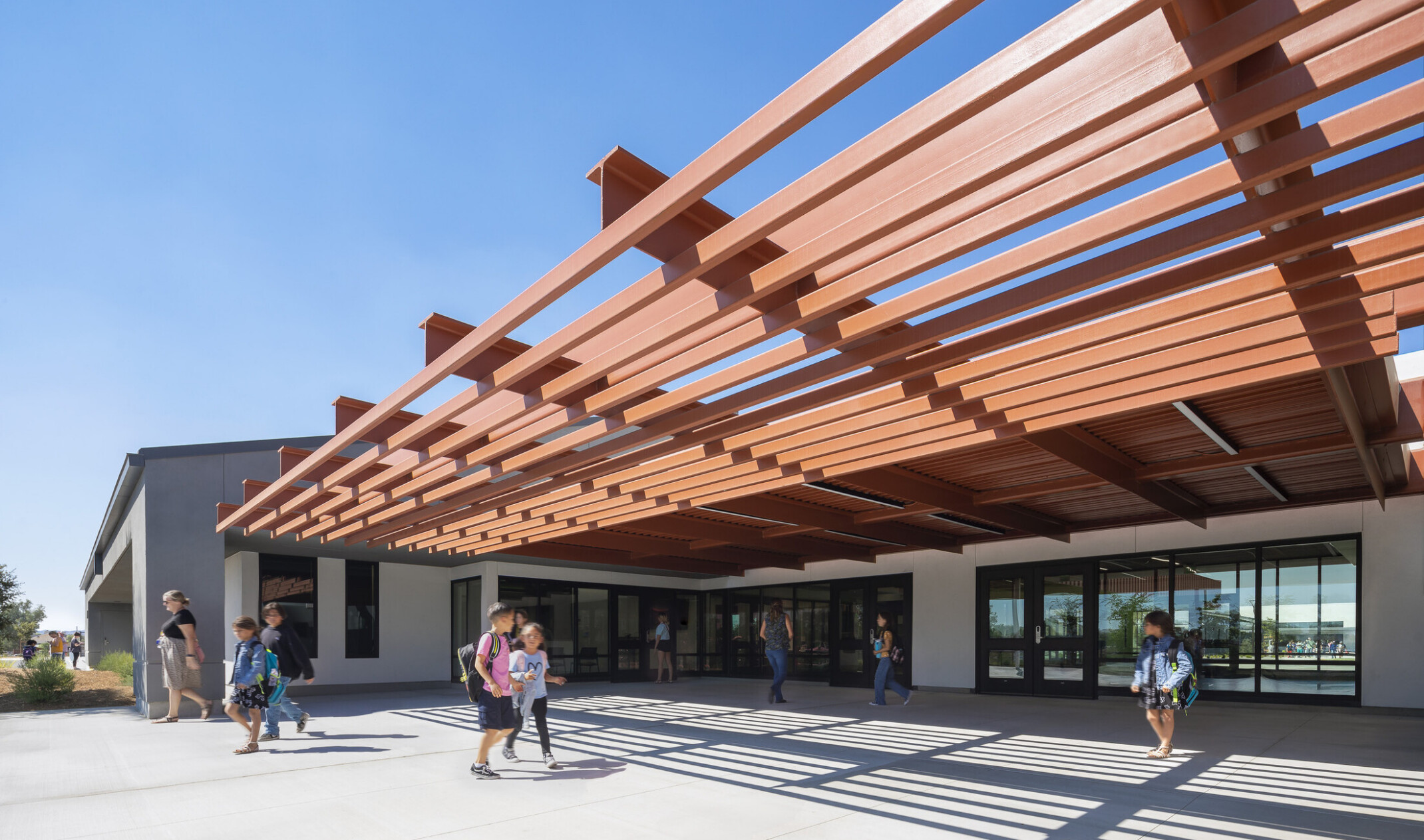 exterior architectural rendering of a school building gathering area; outdoor/indoor learning spaces
