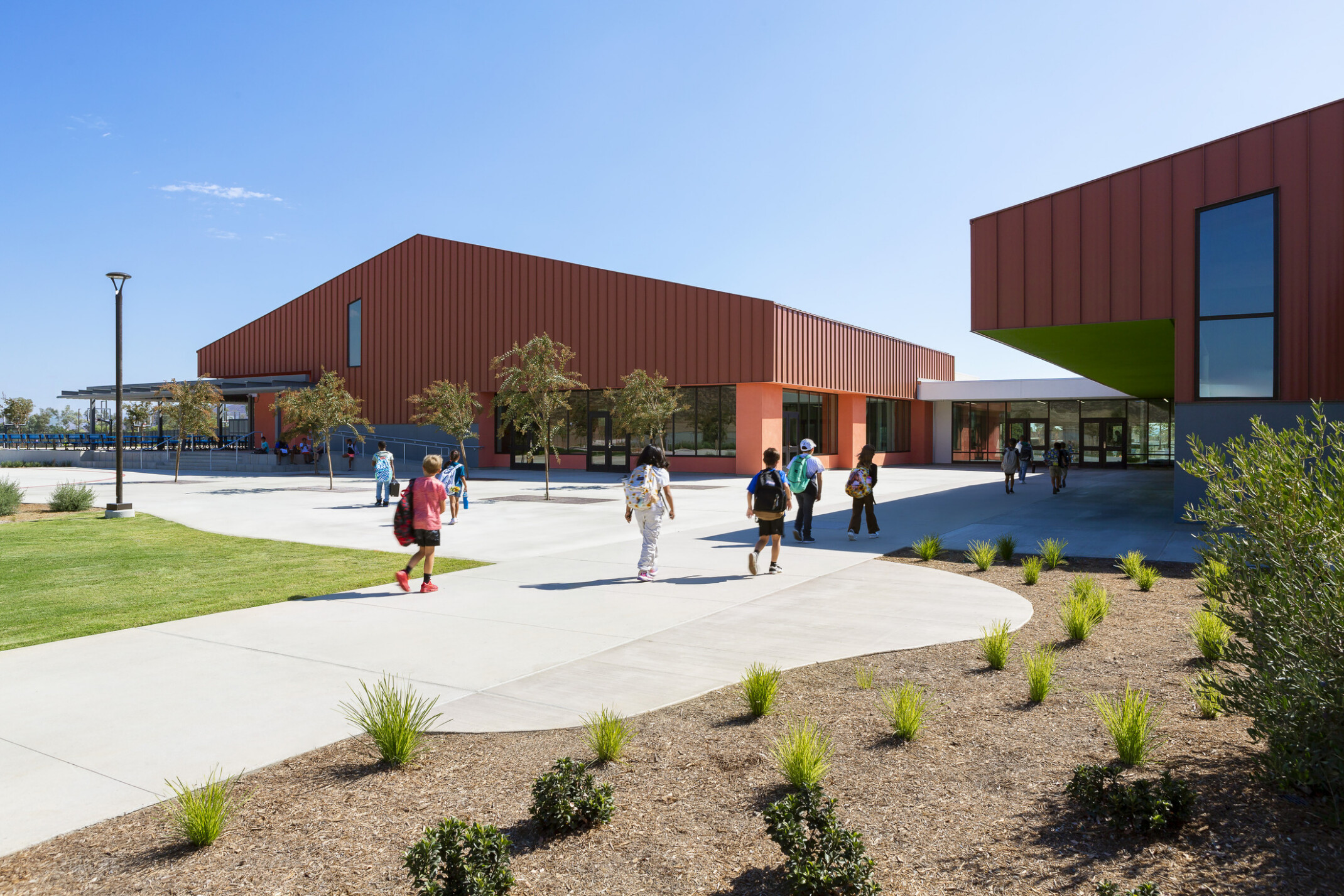 Students walking into the front entrance of a burnt orange color building