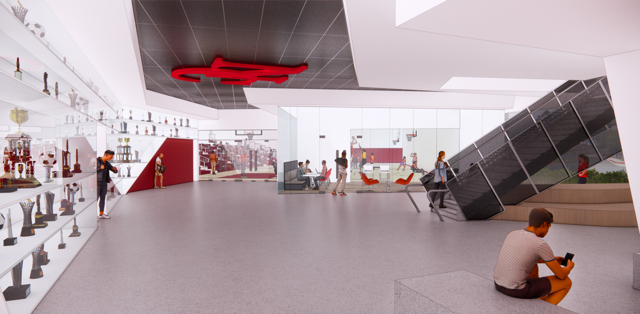 Contemporary athletic facility lobby featuring trophy displays, informal seating, meeting spaces, and a prominent staircase connecting multiple levels
