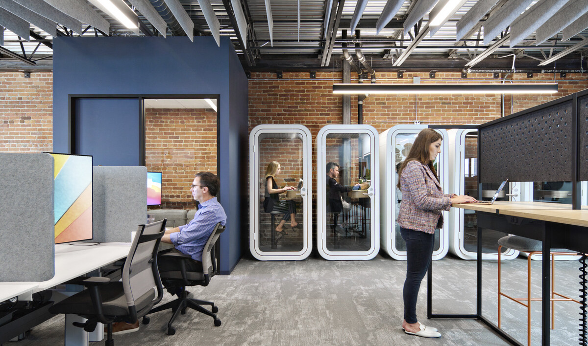 modern workplace with phone booths along the back wall for privacy, standing desks, and optimal lighting; all designed using research