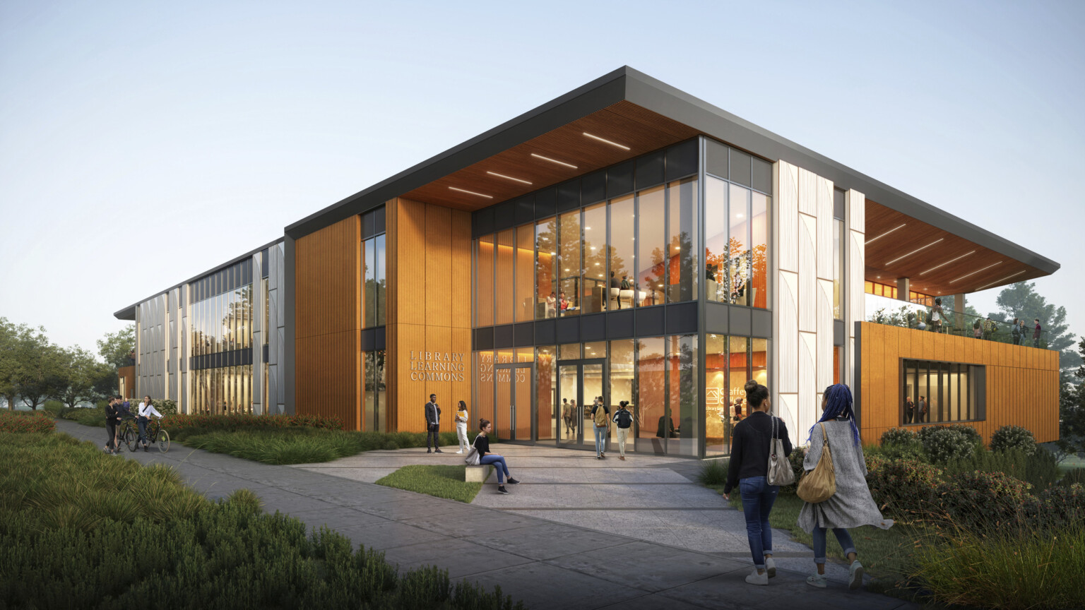 Exterior view of two-story library at dusk, mass timber, floor-to-ceiling glass fenestration, concrete walkway leads to entrance