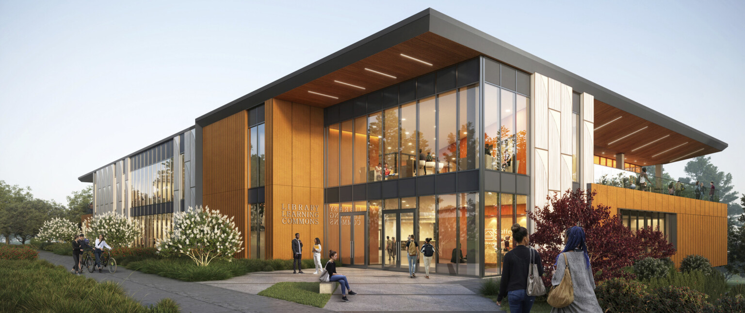 Exterior view of two-story library at dusk, mass timber, floor-to-ceiling glass fenestration, concrete walkway leads to entrance