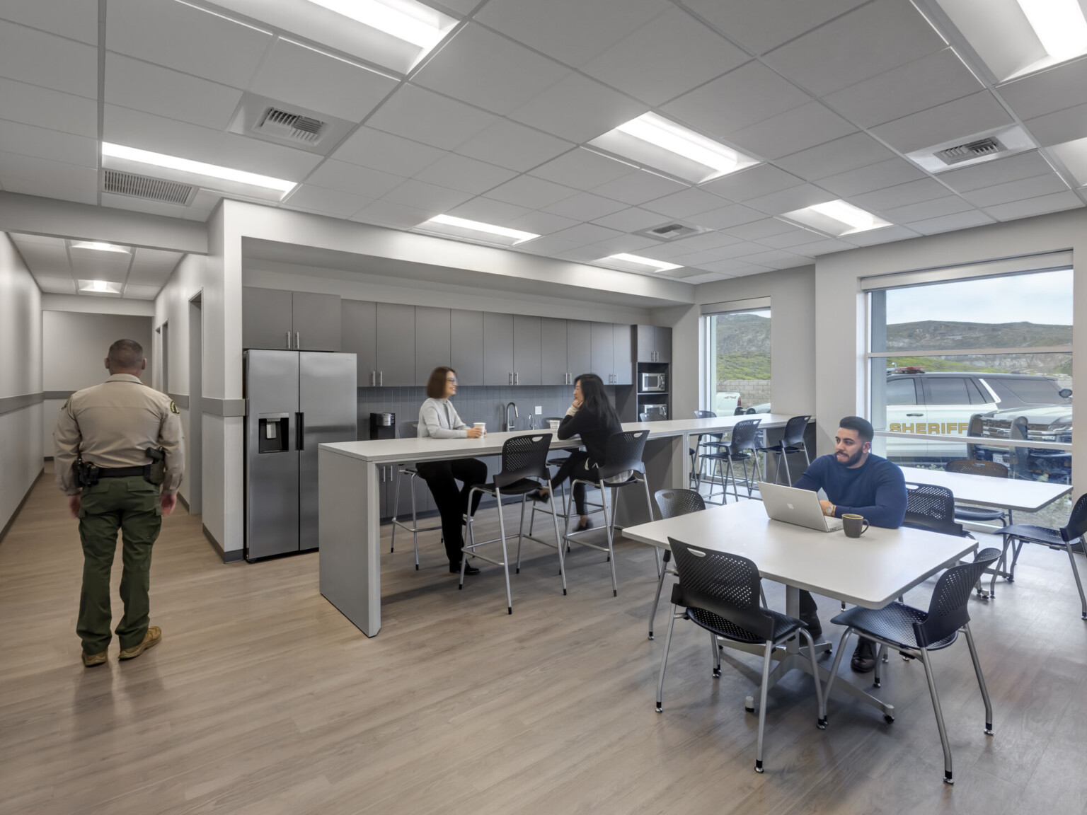 People congregating in renovated break room with kitchen amenities, large windows, day lit, dining tables and seating