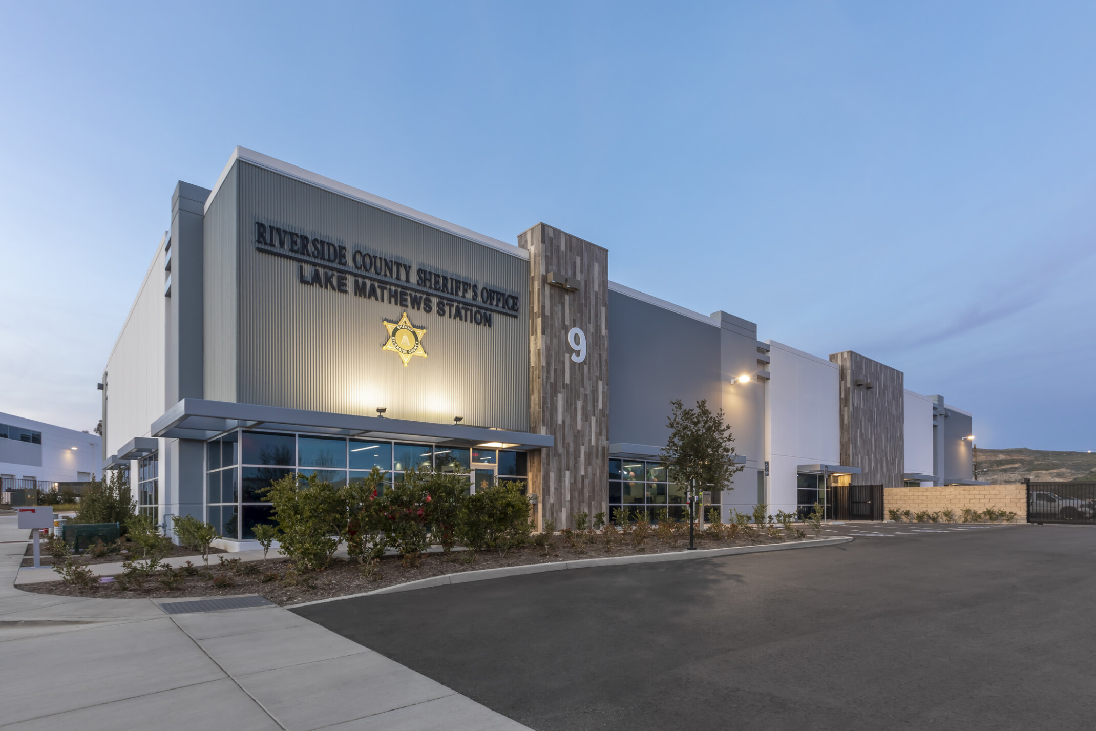 An exterior of the building renovation at night, uplighting on station signage, expanded parking lot