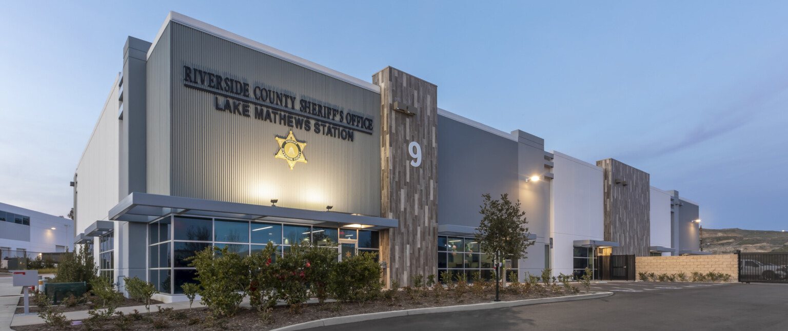 An exterior of the building renovation at night, uplighting on station signage, expanded parking lot