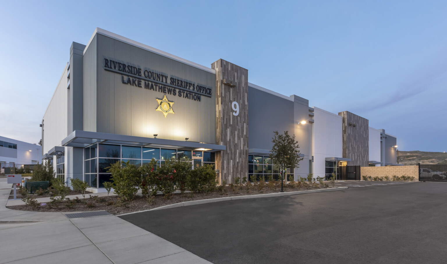 An exterior of the building renovation at night, uplighting on station signage, expanded parking lot
