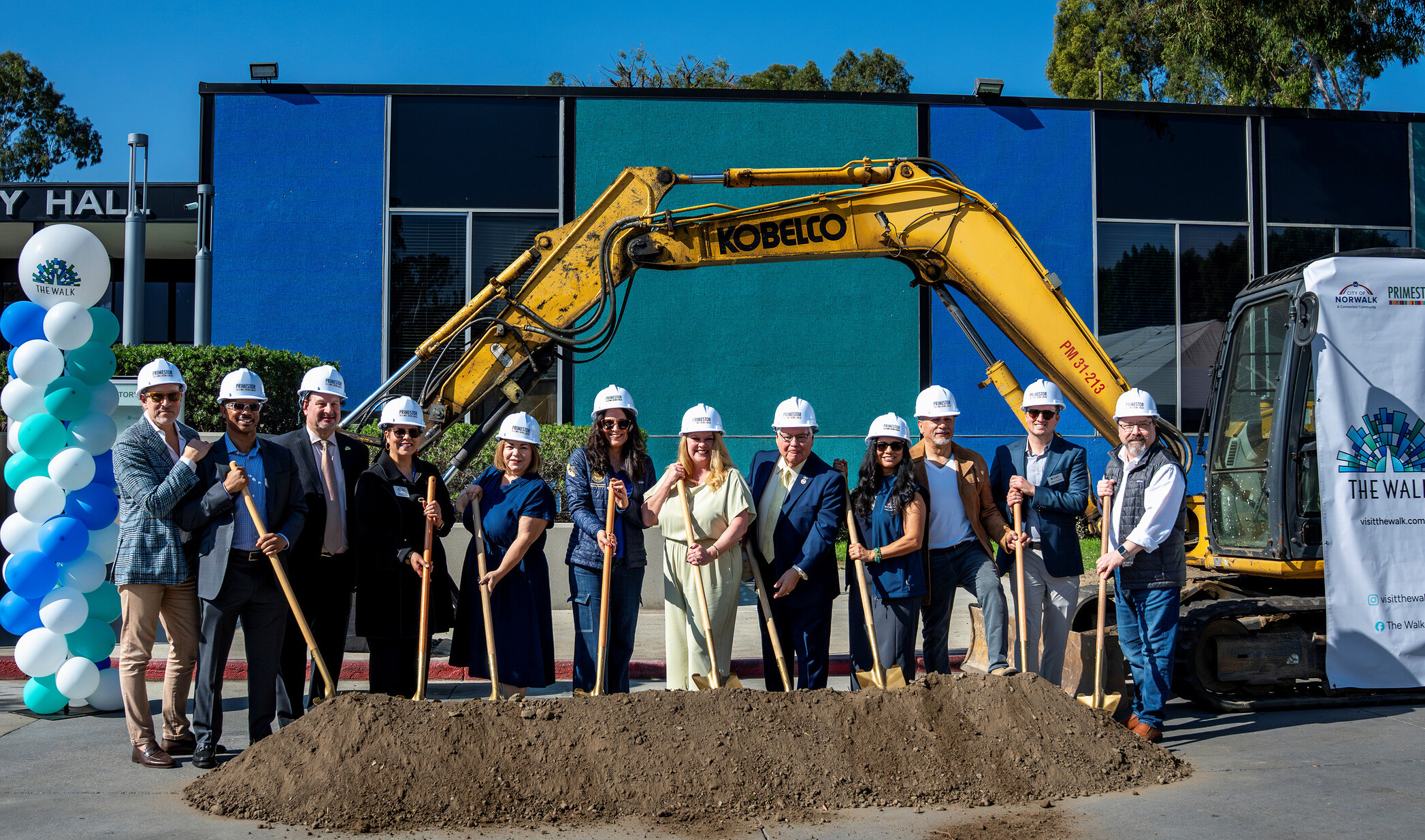 people standing on top of a pile of dirt holding shovels to recognize ground breaking