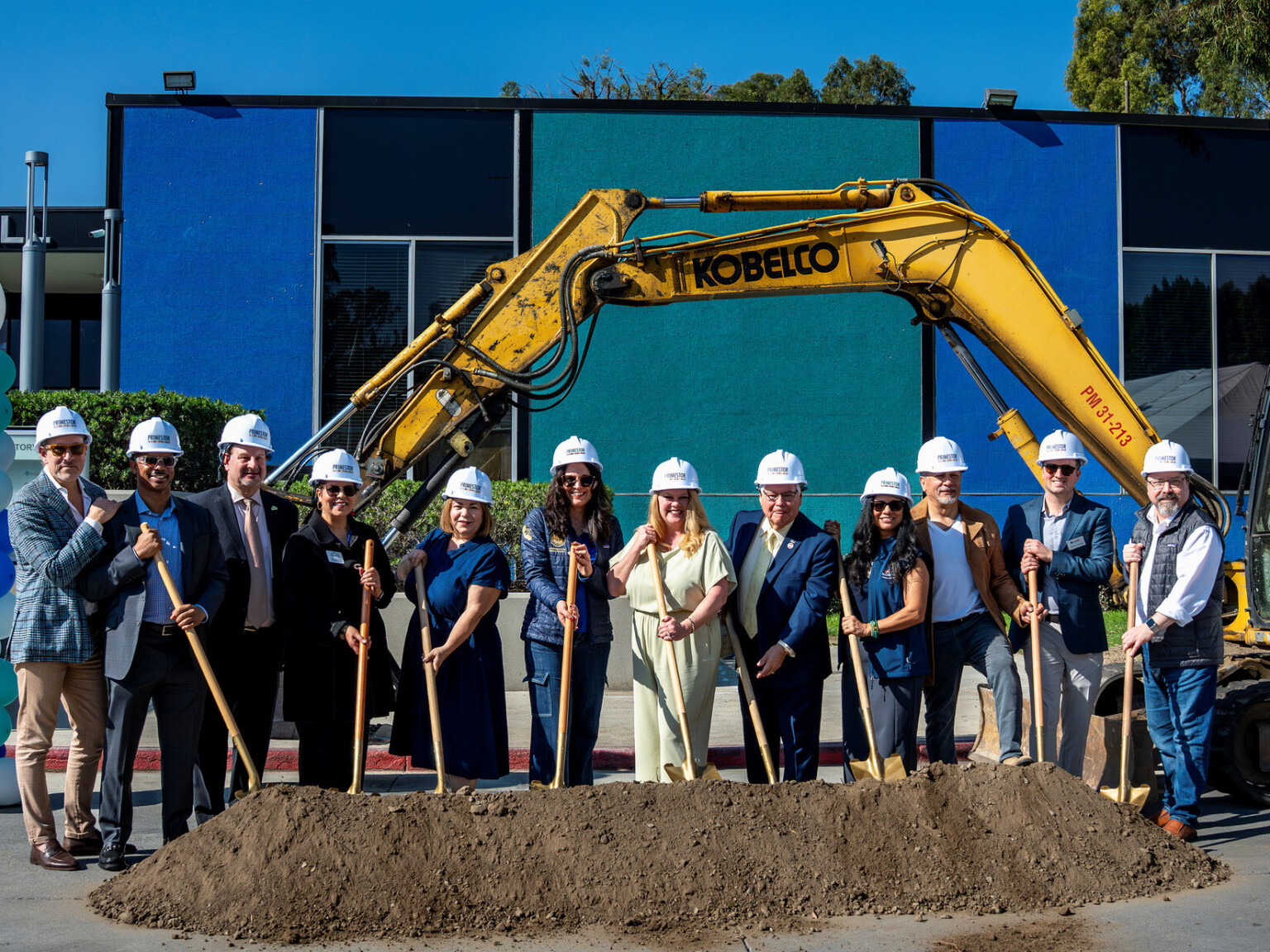 people standing on top of a pile of dirt holding shovels to recognize ground breaking